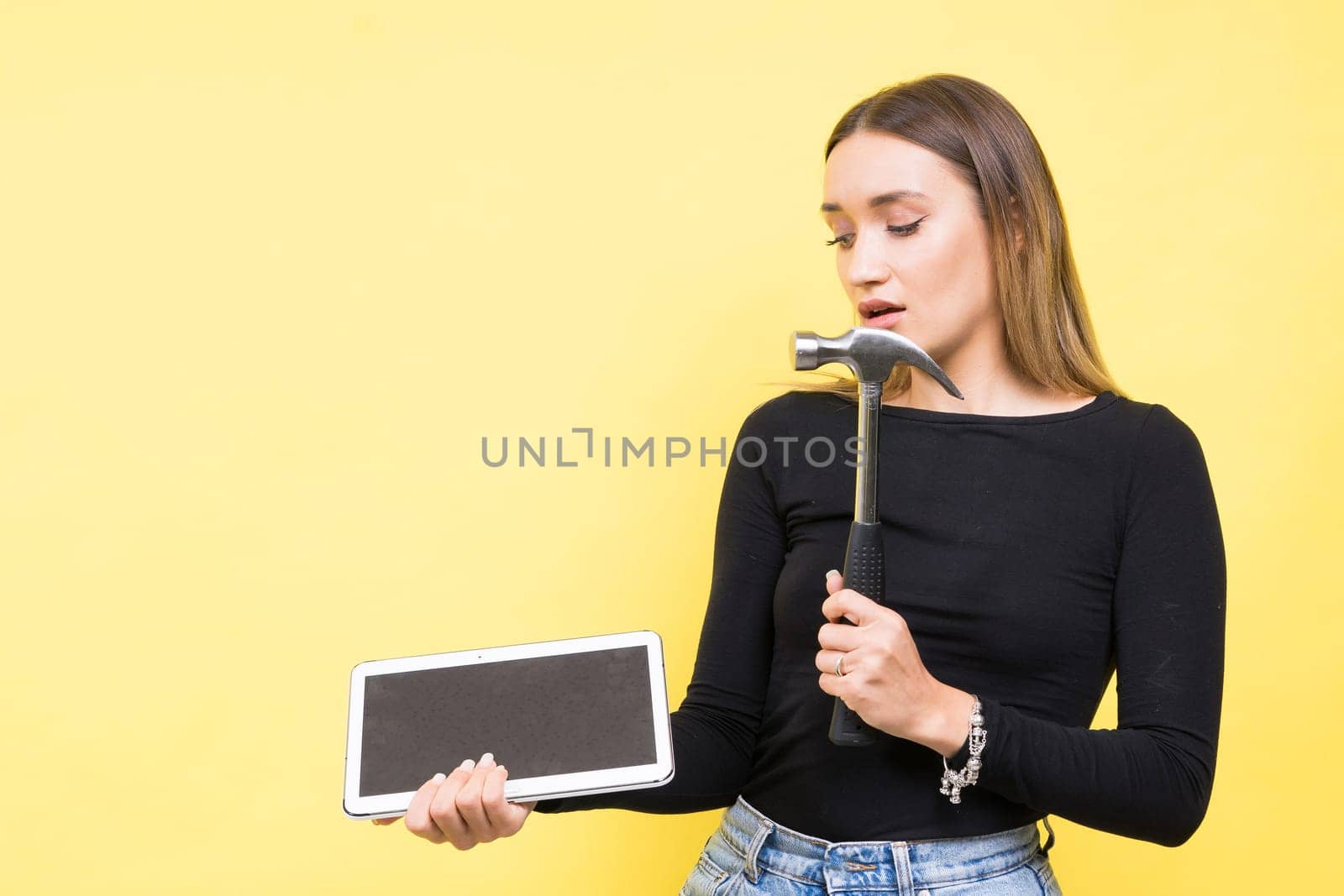 Woman with tablet and a hammer, Studio lighting yellow background isolated, copy space