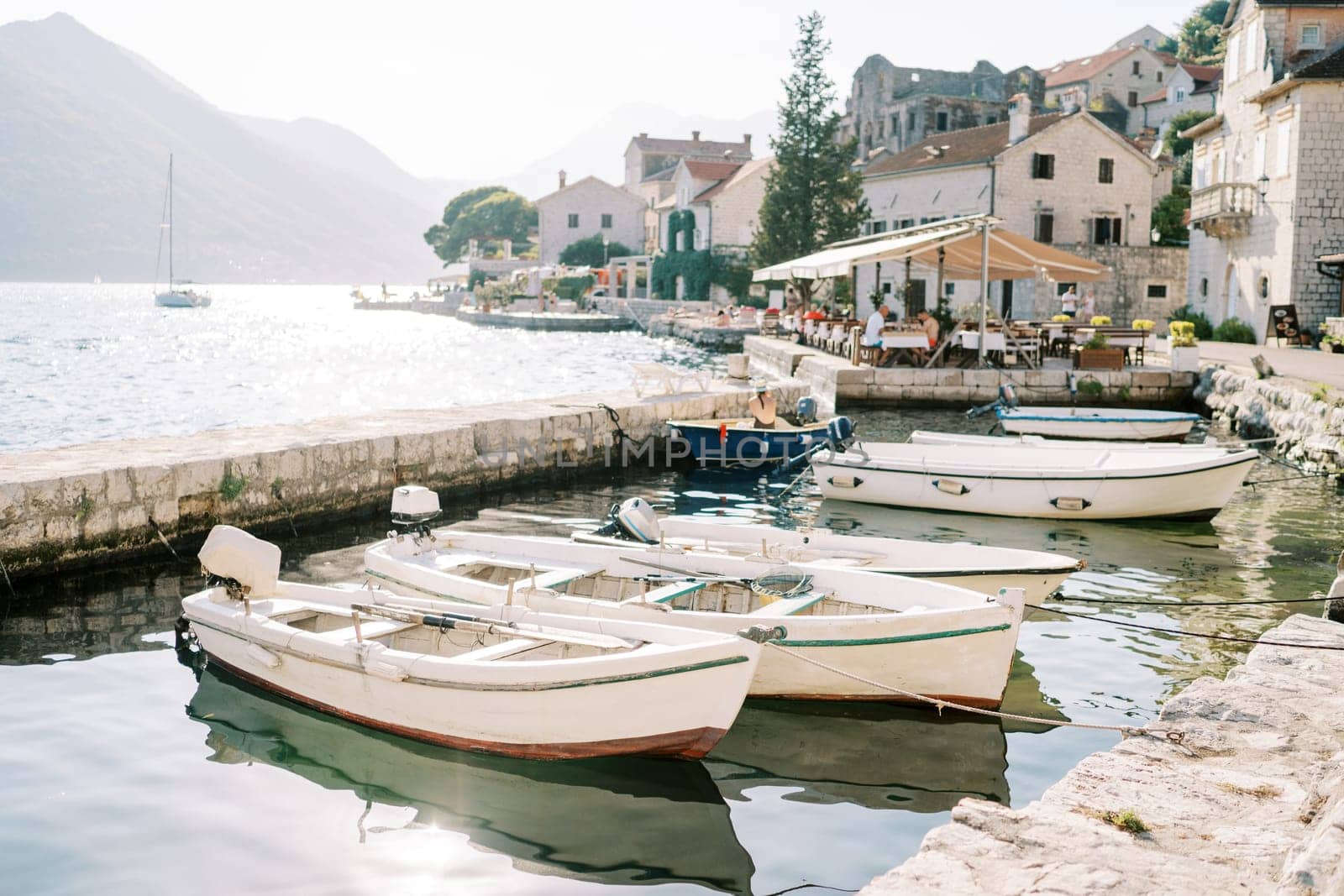 Fishing boats are moored in a row off the coast of Perast. Montenegro by Nadtochiy