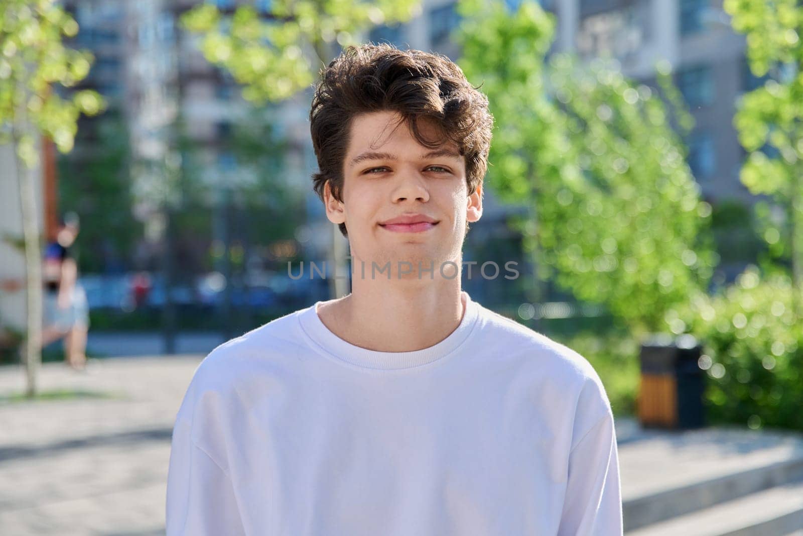 Headshot portrait of handsome guy 19, 20 years old, looking at camera outdoors by VH-studio