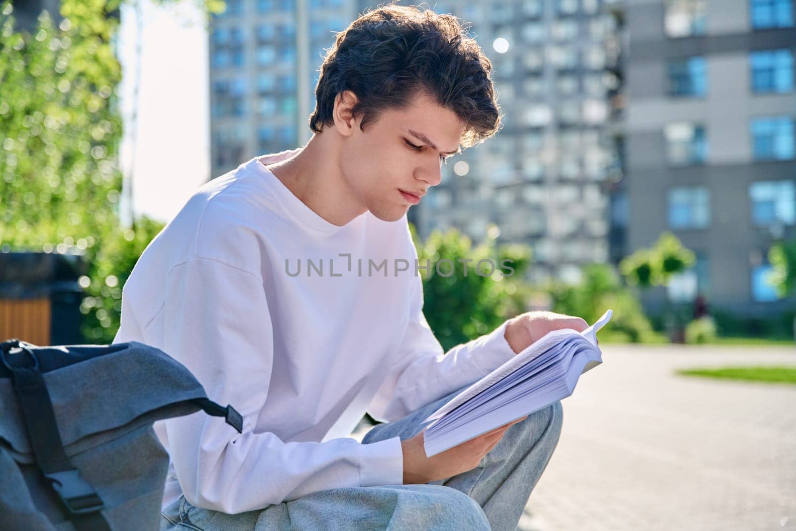 Handsome young male university college student reading a book by VH-studio