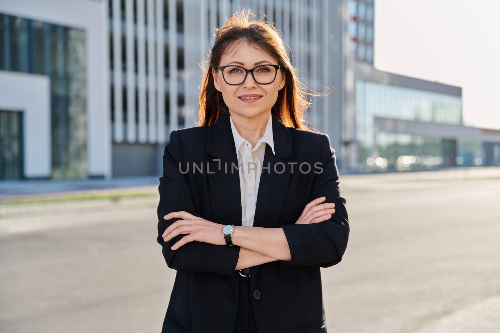 Portrait of middle-aged business confident woman in suit, with crossed arms, posing outdoors in urban style. Office employee worker businesswoman teacher entrepreneur economist banker financier lawyer
