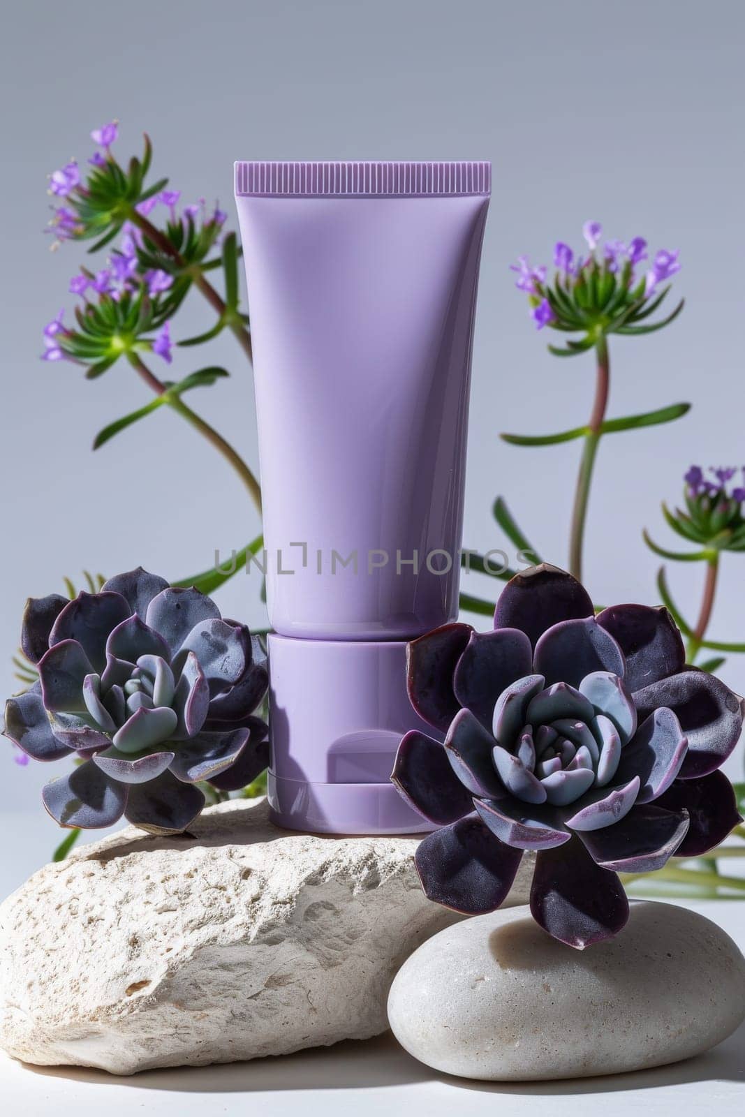 A small purple tube of lotion sits on a rock next to purple flowers by itchaznong