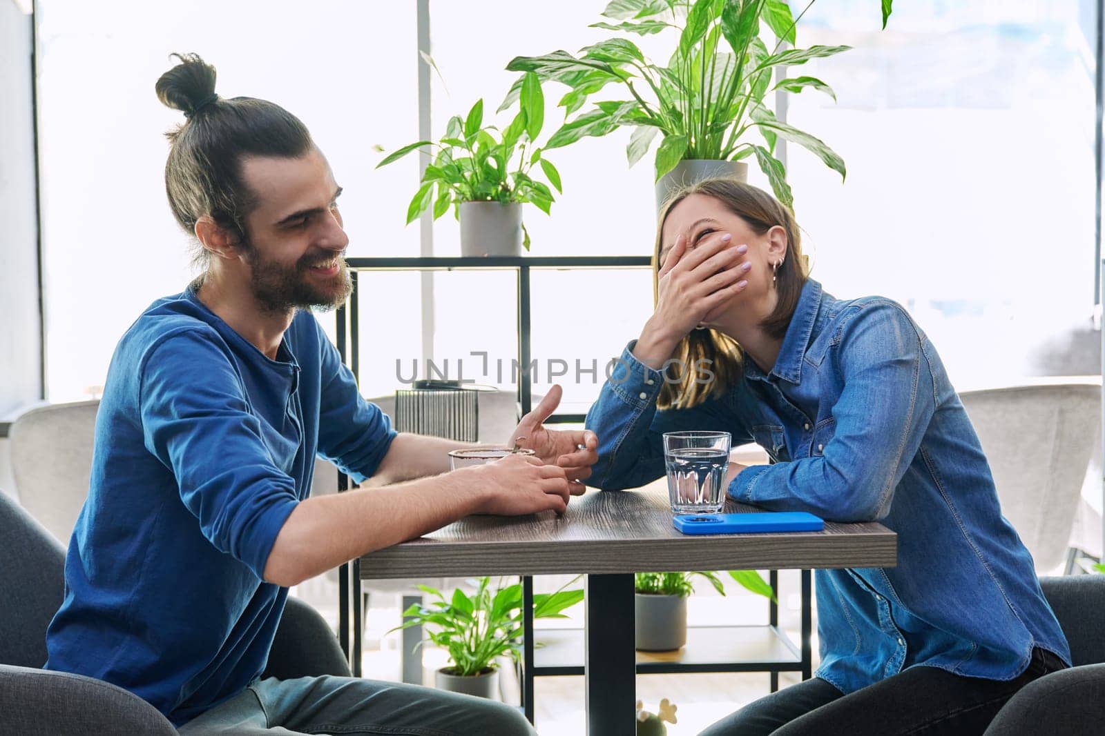 Laughing rejoicing cheerful young couple sitting together at table in cafe. Joyful emotions, enjoyment, friendship, happiness, love, togetherness, lifestyle relationships communication youth concept