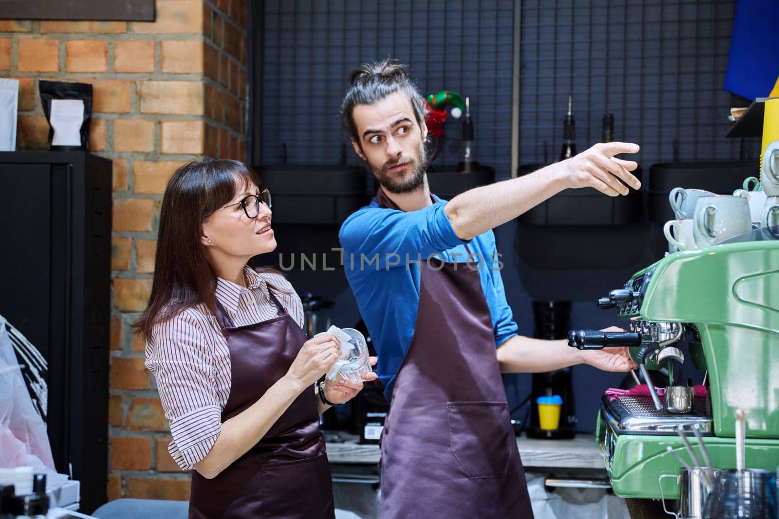 Teamwork, man and woman in aprons working together at bar counter in coffee shop cafe by VH-studio