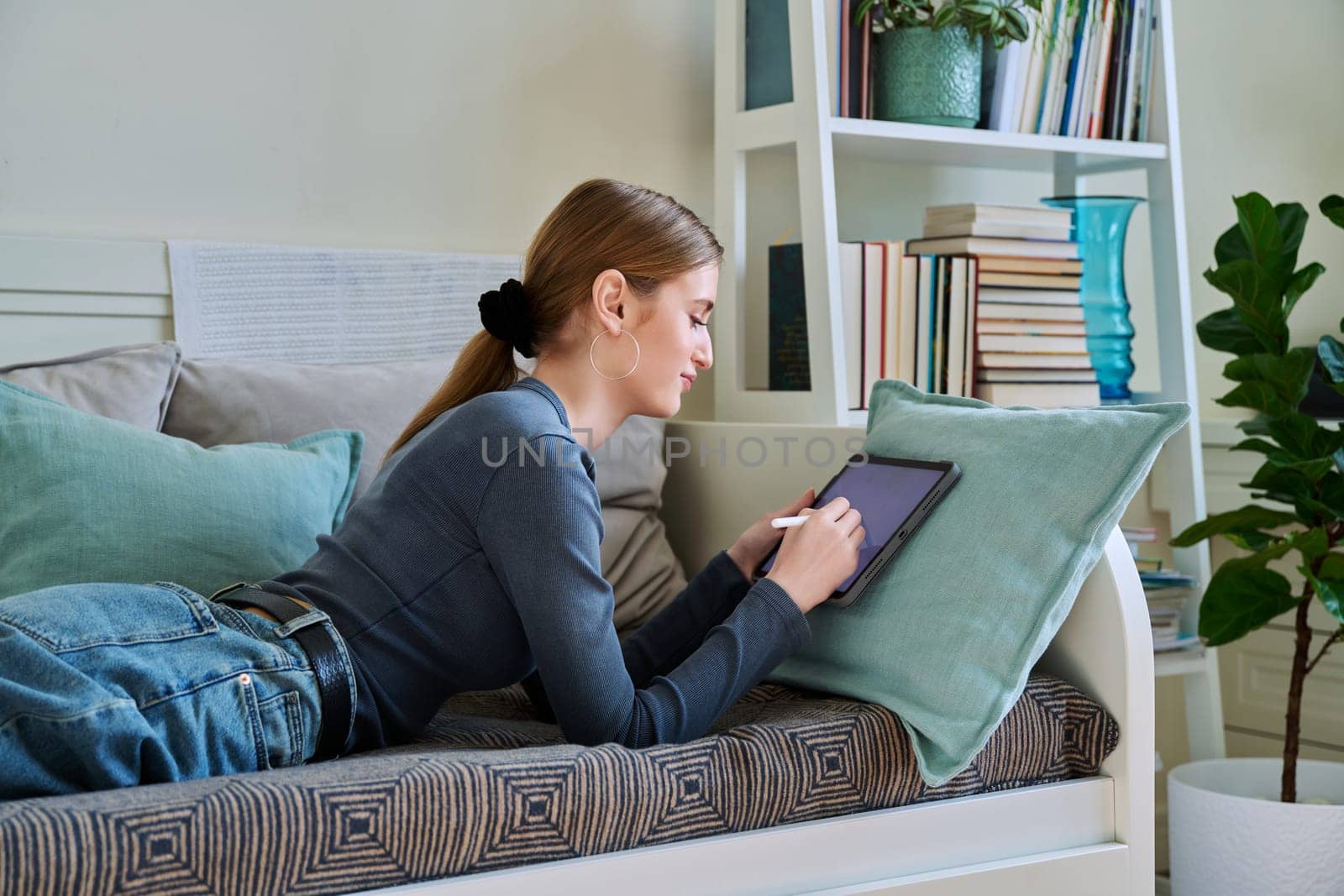 Young female teenager with digital tablet, stylus drawing illustrating at home by VH-studio
