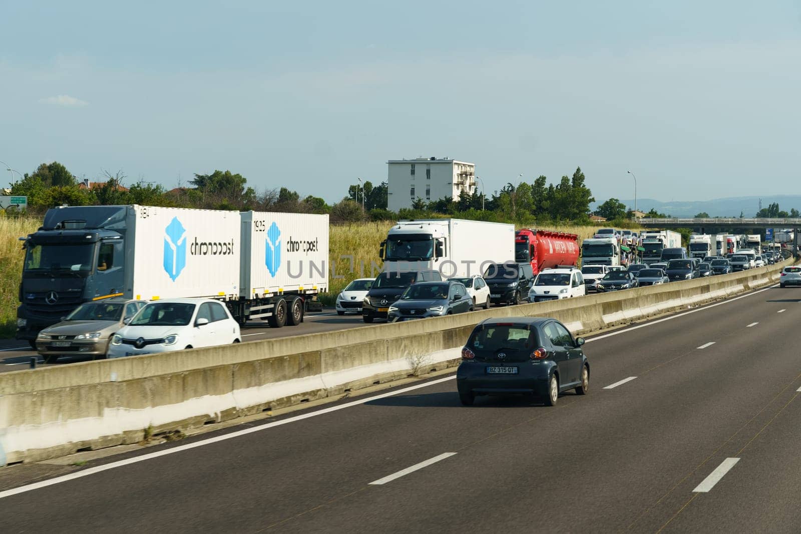 Vaugry Gard, France - May 30, 2023: A congested highway filled with heavy traffic runs alongside towering urban buildings, showcasing the hustle and bustle of city life.