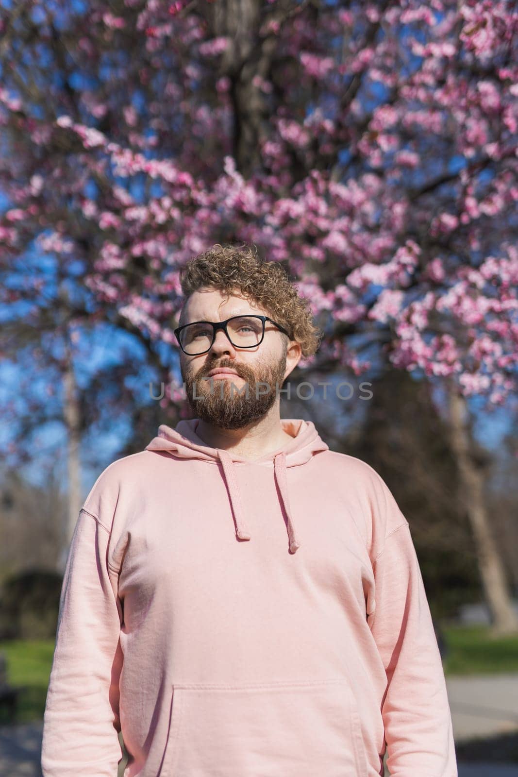 Man allergic enjoying after treatment from seasonal allergy at spring. Portrait of happy bearded man smiling in front of blossom tree at springtime. Spring blooming and allergy concept. Copy space.