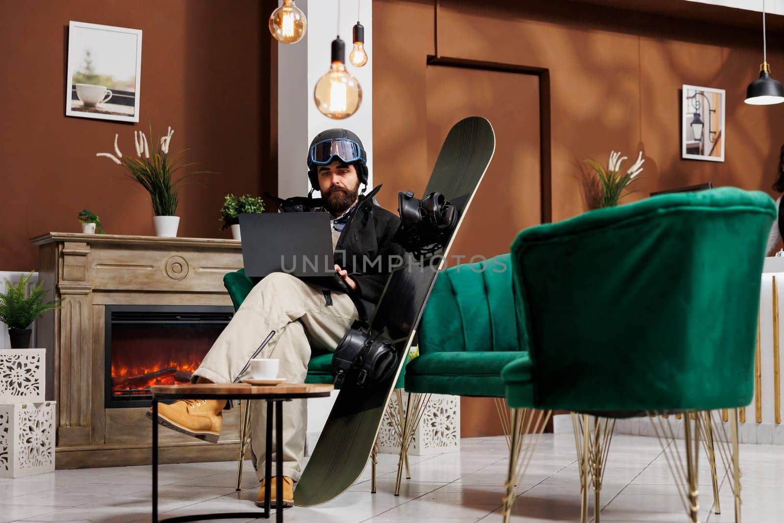 Man with laptop in ski resort lounge by DCStudio