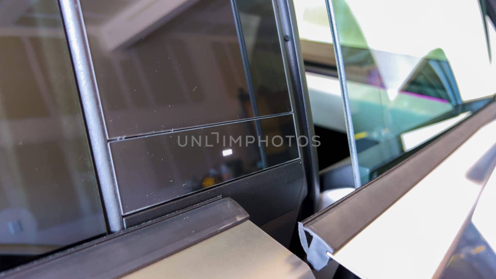 Denver, Colorado, USA-April 28, 2024- This close-up captures the distinctive window and frame design of the Tesla Cybertruck, highlighting its sleek lines and industrial aesthetic, reflected in the glass and metal structures.