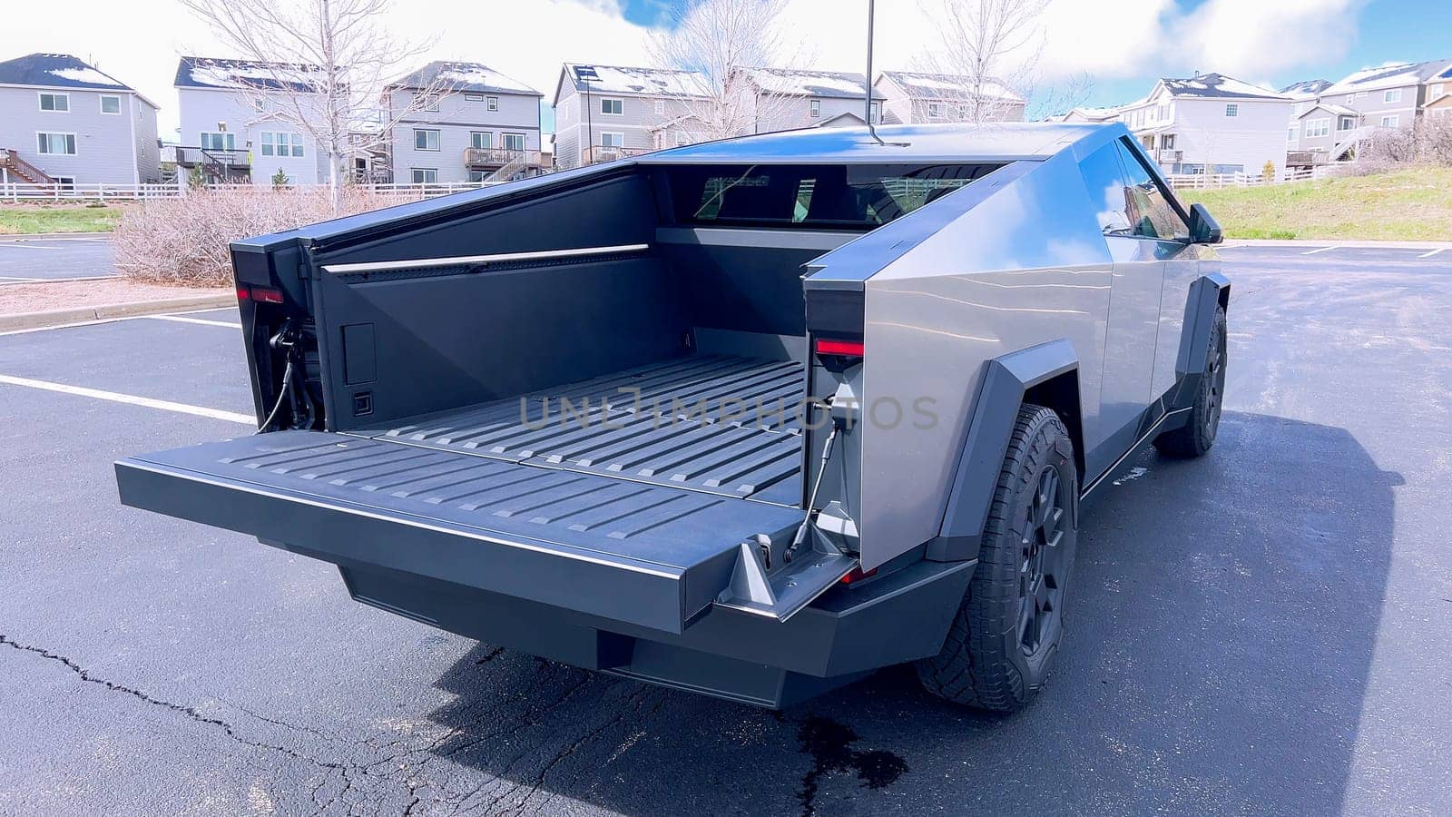 Denver, Colorado, USA-April 28, 2024- Showcasing the utility of the Tesla Cybertruck, this image features the vehicle open cargo bed, highlighting its spacious and functional design, parked in a suburban area with homes in the background.