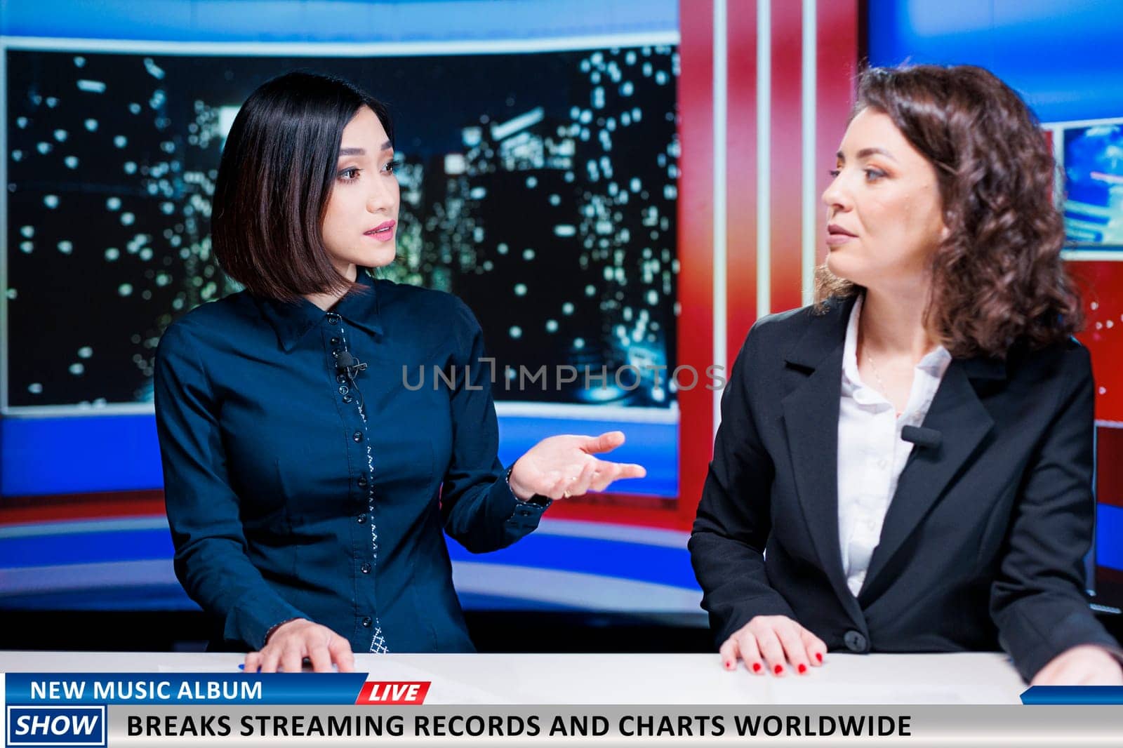 Journalists team talk about new music album, women night show hosts reveal song breaking top charts and records at global scale. Newscasters discuss about streaming and selling success.