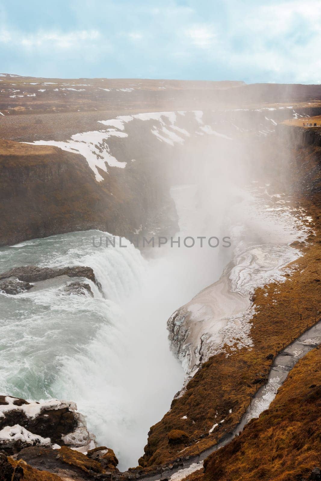 Picturesque Gullfoss waterfall in arctic wilderness offers icelandic landscape with snow covered pastures and frozen water pouring from hills. Northern beauty on hillside in Iceland.