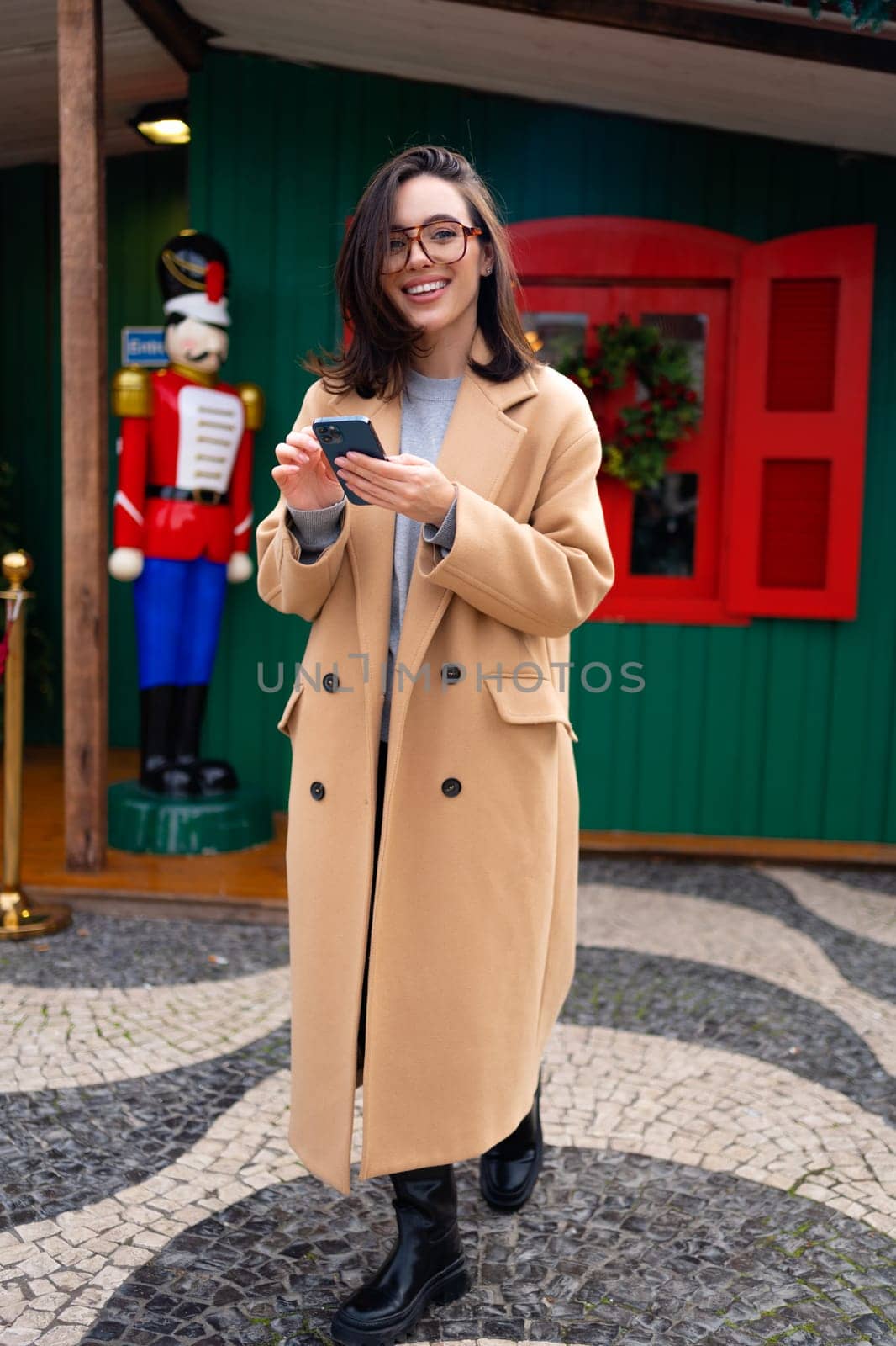 Woman in glasses using mobile phone at day in the city by andreonegin