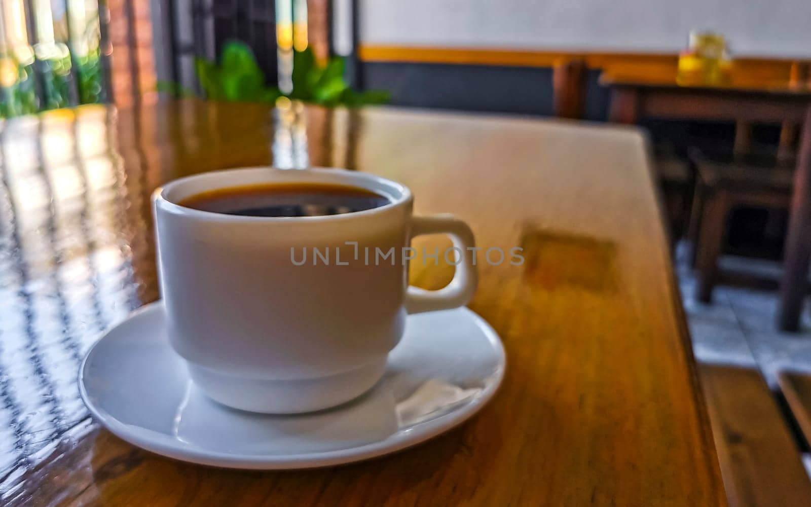 White cup of black Americano coffee on a wooden table in Alajuela Costa Rica in Central America.