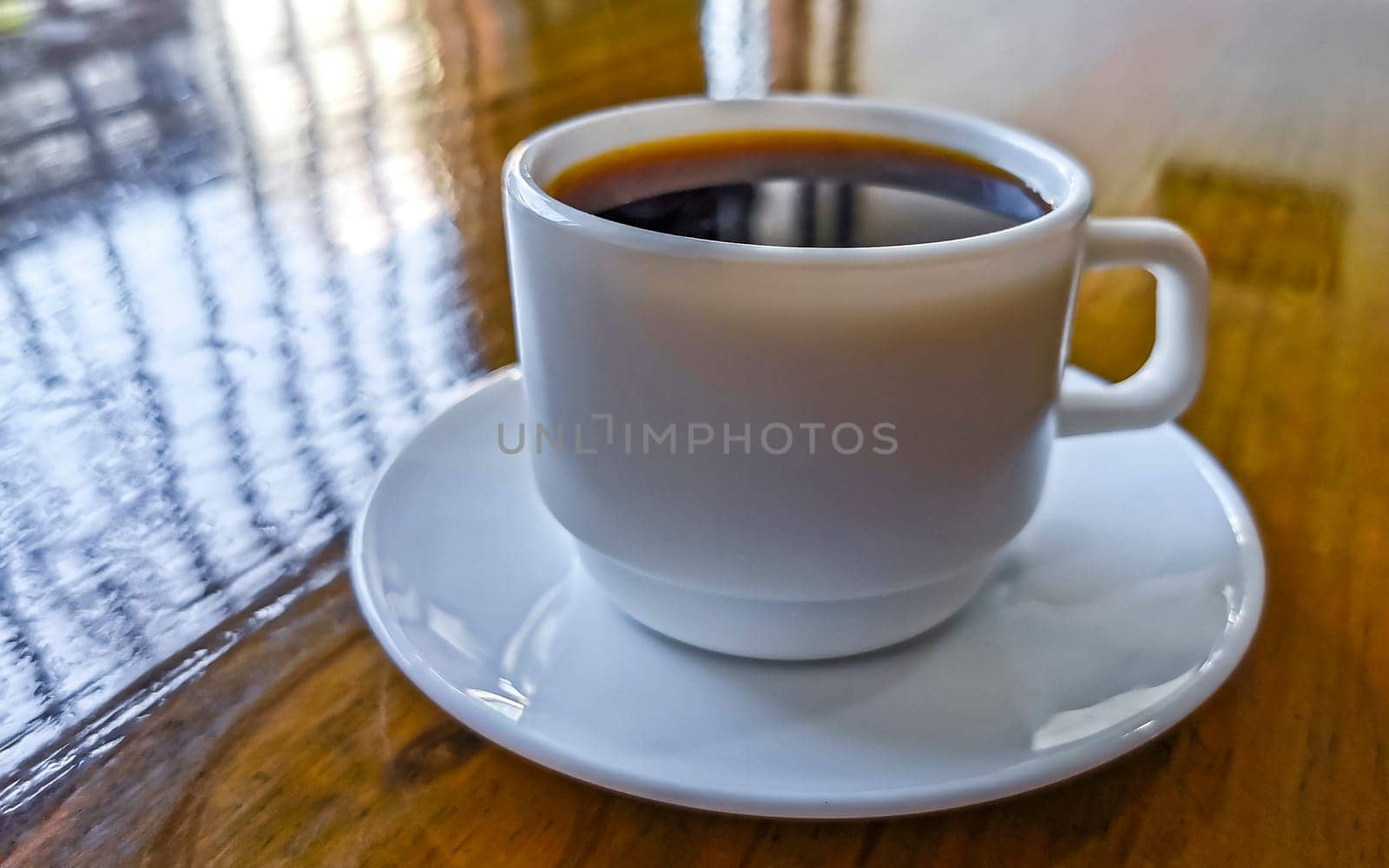 White cup of black Americano coffee on a wooden table in Alajuela Costa Rica in Central America.