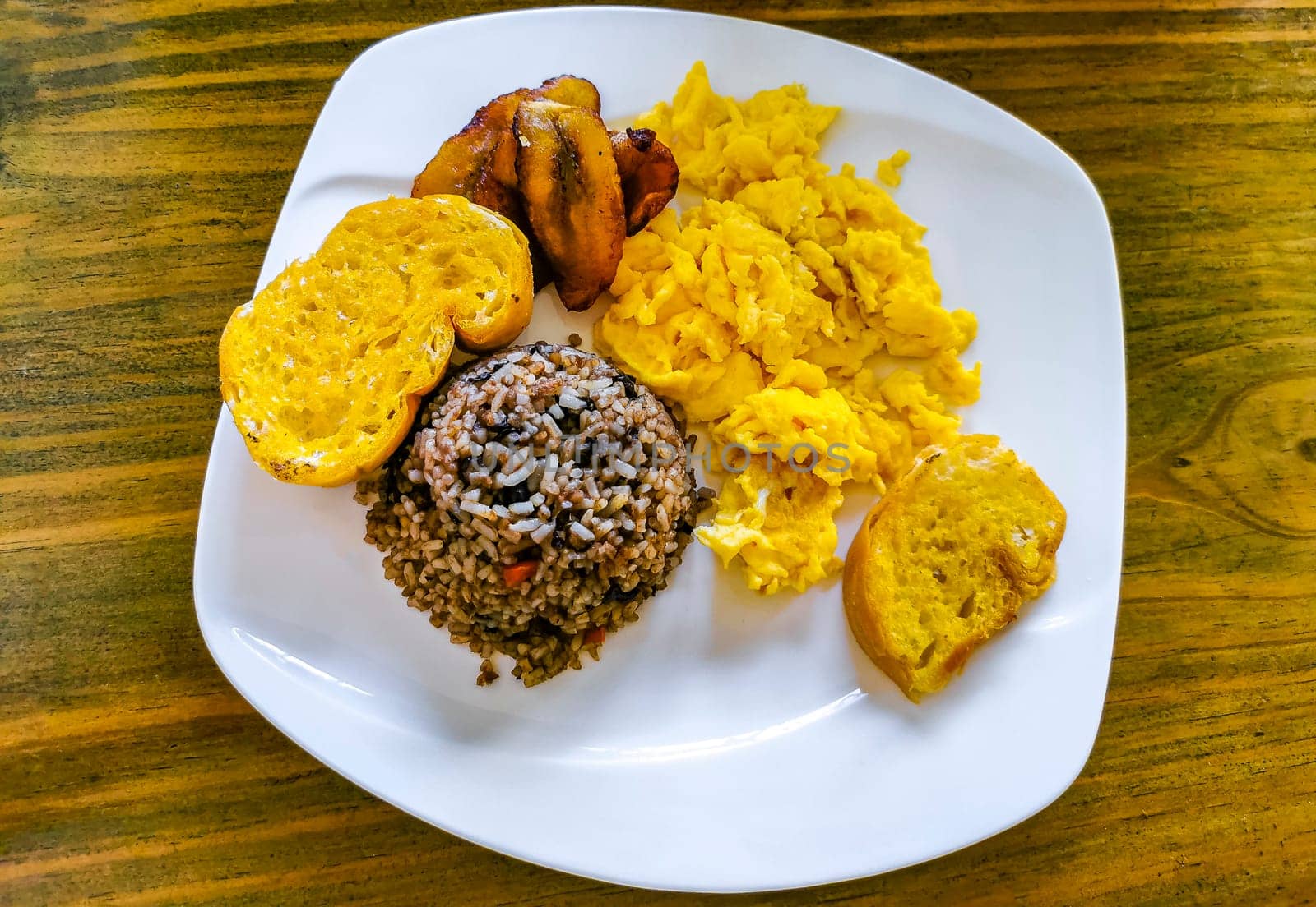Costa Rican food dish Rice Banana Scrambled eggs Beans bread. by Arkadij
