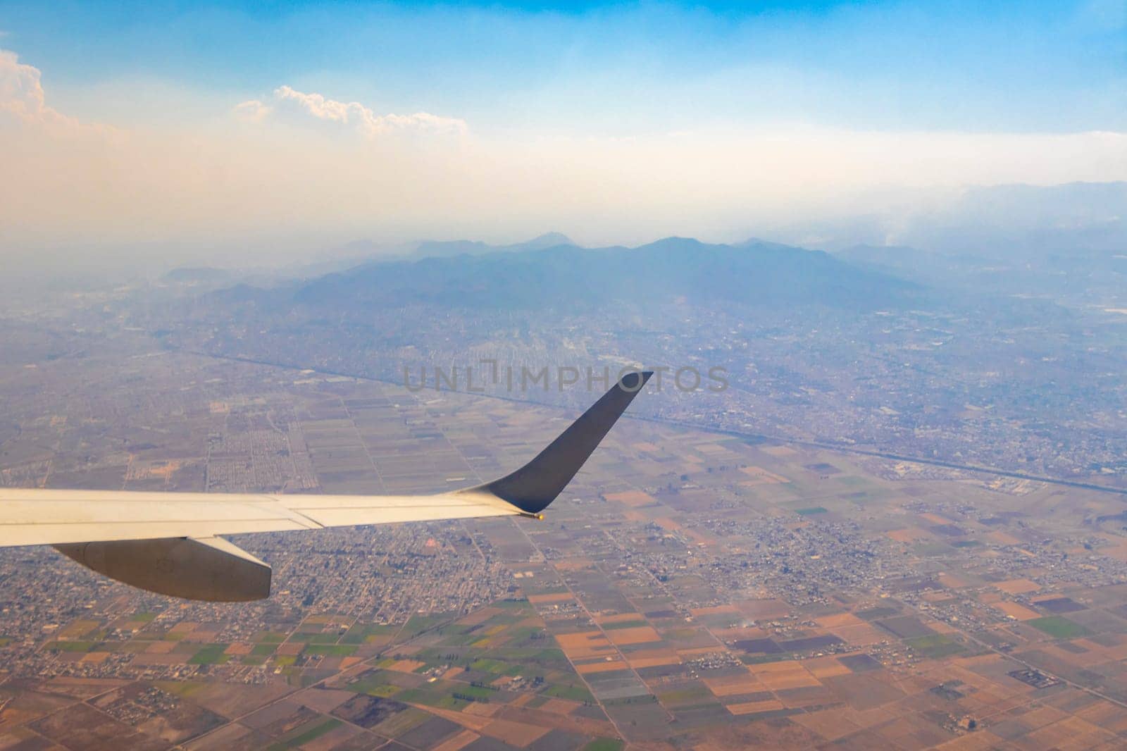 Flying in an airplane over Mexico Clouds Sky Volcanoes Mountains City and desert in Mexico.