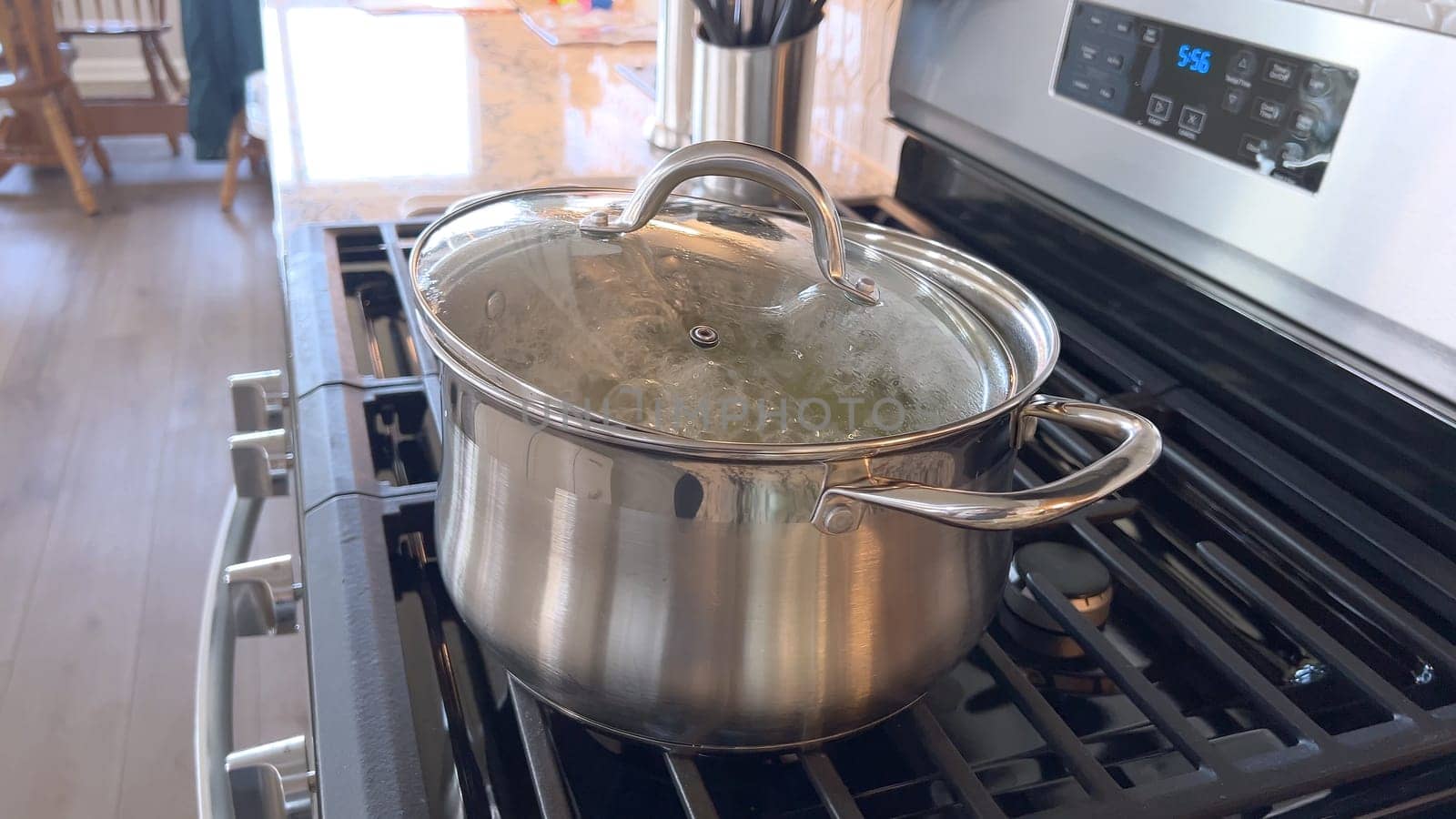 Captured in a home kitchen, this image features a stainless steel pot with boiling water on a gas stove, showcasing a common culinary preparation step with steam rising from the pot under natural light.