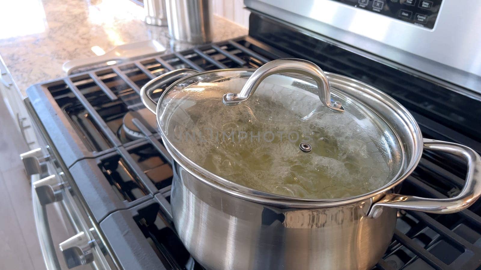 Captured in a home kitchen, this image features a stainless steel pot with boiling water on a gas stove, showcasing a common culinary preparation step with steam rising from the pot under natural light.