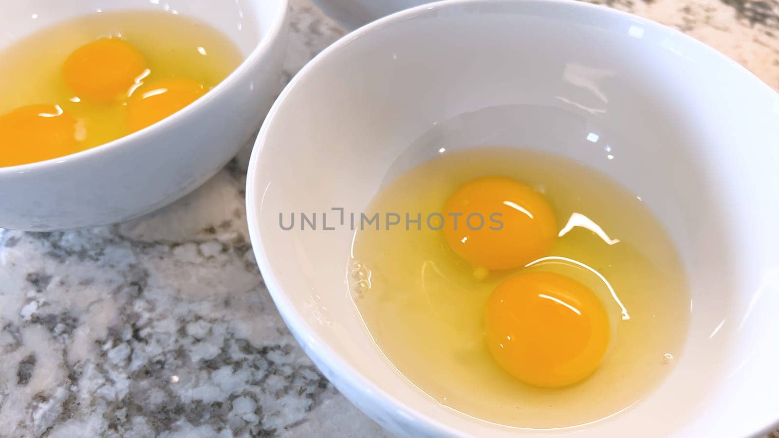 Three Fresh Eggs Cracked Open in a White Bowl for Cooking by arinahabich