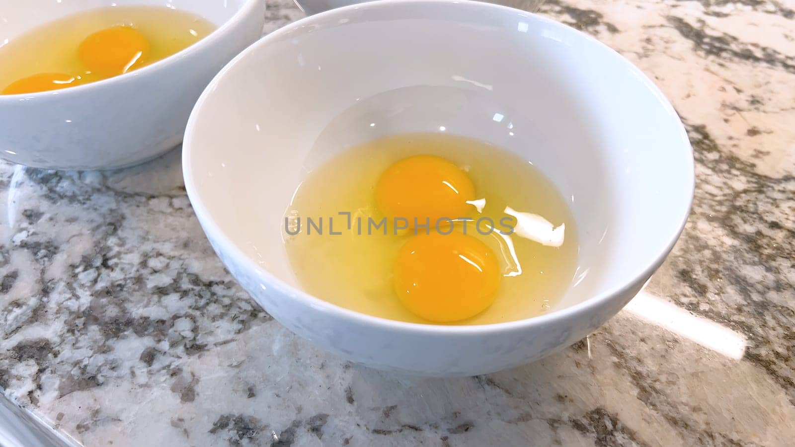 Three Fresh Eggs Cracked Open in a White Bowl for Cooking by arinahabich