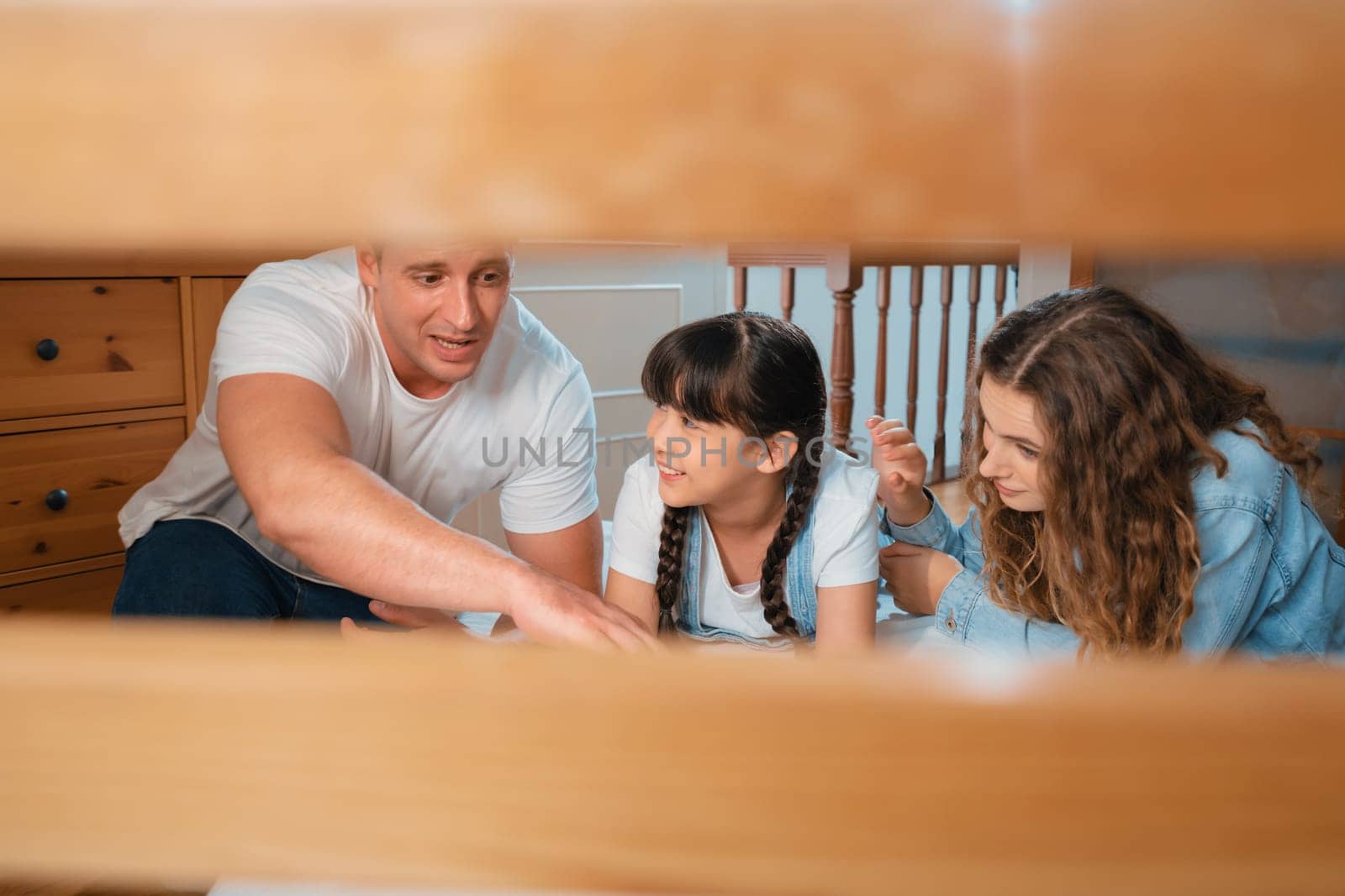 Bedtime story with childhood storytelling, mom and dad reading a fantasy book together to their little young girl in cozy and comfortable bedroom. Modern family happy time. Panorama Synchronos