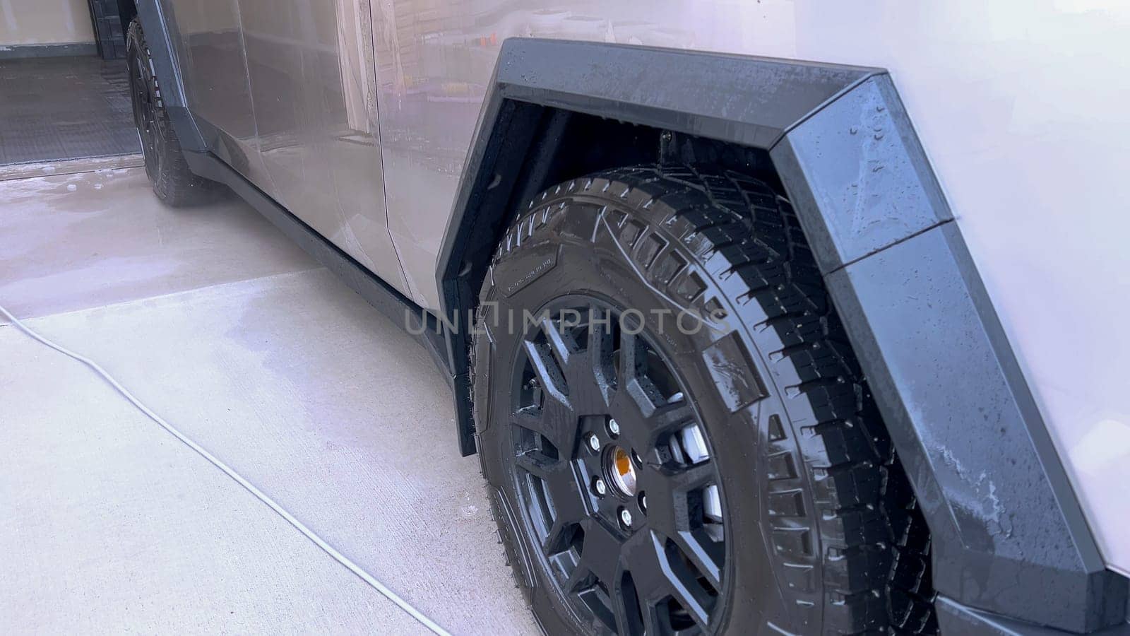 Denver, Colorado, USA-April 28, 2024- This image captures a Tesla Cybertruck undergoing a thorough cleaning, focusing on the high-pressure washing of its cargo bed, demonstrating the maintenance of its durable and robust design. High-Pressure Cleaning of the Tesla Cybertruck Cargo Bed. High quality photo