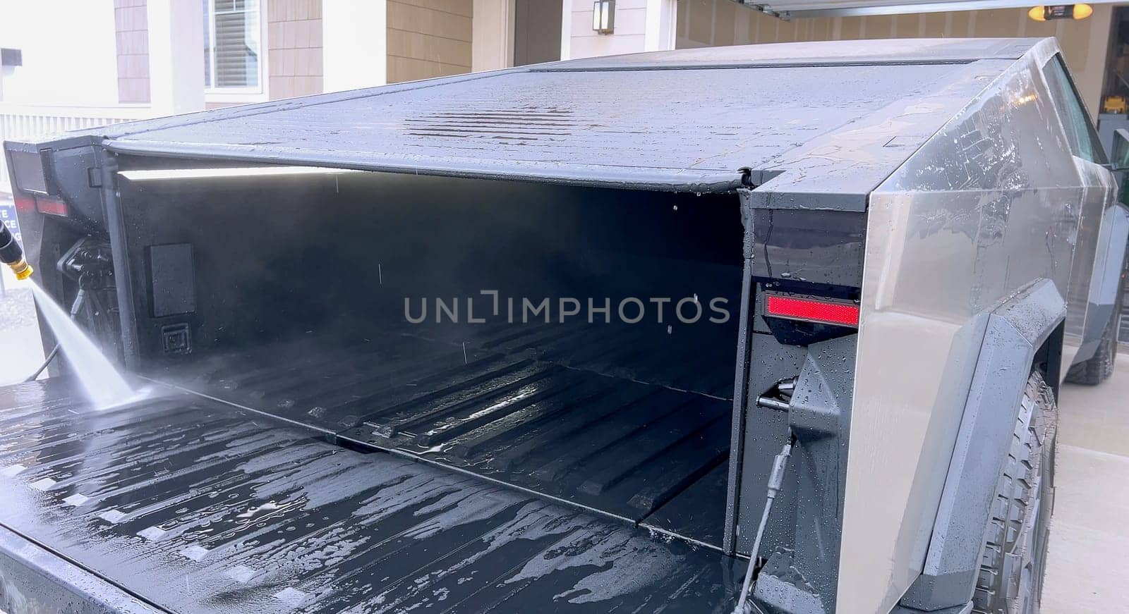 Denver, Colorado, USA-April 28, 2024- This image captures a Tesla Cybertruck undergoing a thorough cleaning, focusing on the high-pressure washing of its cargo bed, demonstrating the maintenance of its durable and robust design. High-Pressure Cleaning of the Tesla Cybertruck Cargo Bed. High quality photo