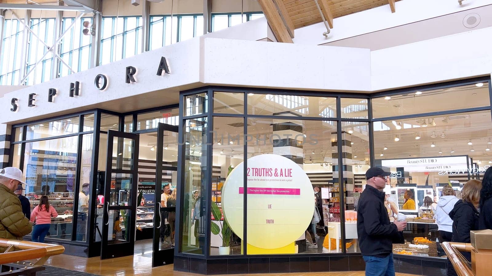 Denver, Colorado, USA-April 28, 2024- Capturing the expansive and airy interior of Park Meadows Mall, this image highlights the modern architectural style with wooden beams, large hanging lights, and a series of vibrant hanging ribbons, creating a lively shopping atmosphere.