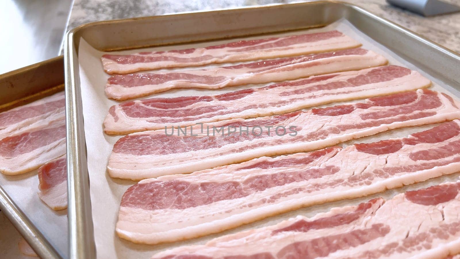 Neatly arranged raw bacon strips on a baking tray, prepared for cooking, capturing the fresh, uncooked look of this popular breakfast ingredient before it turns crispy and golden.