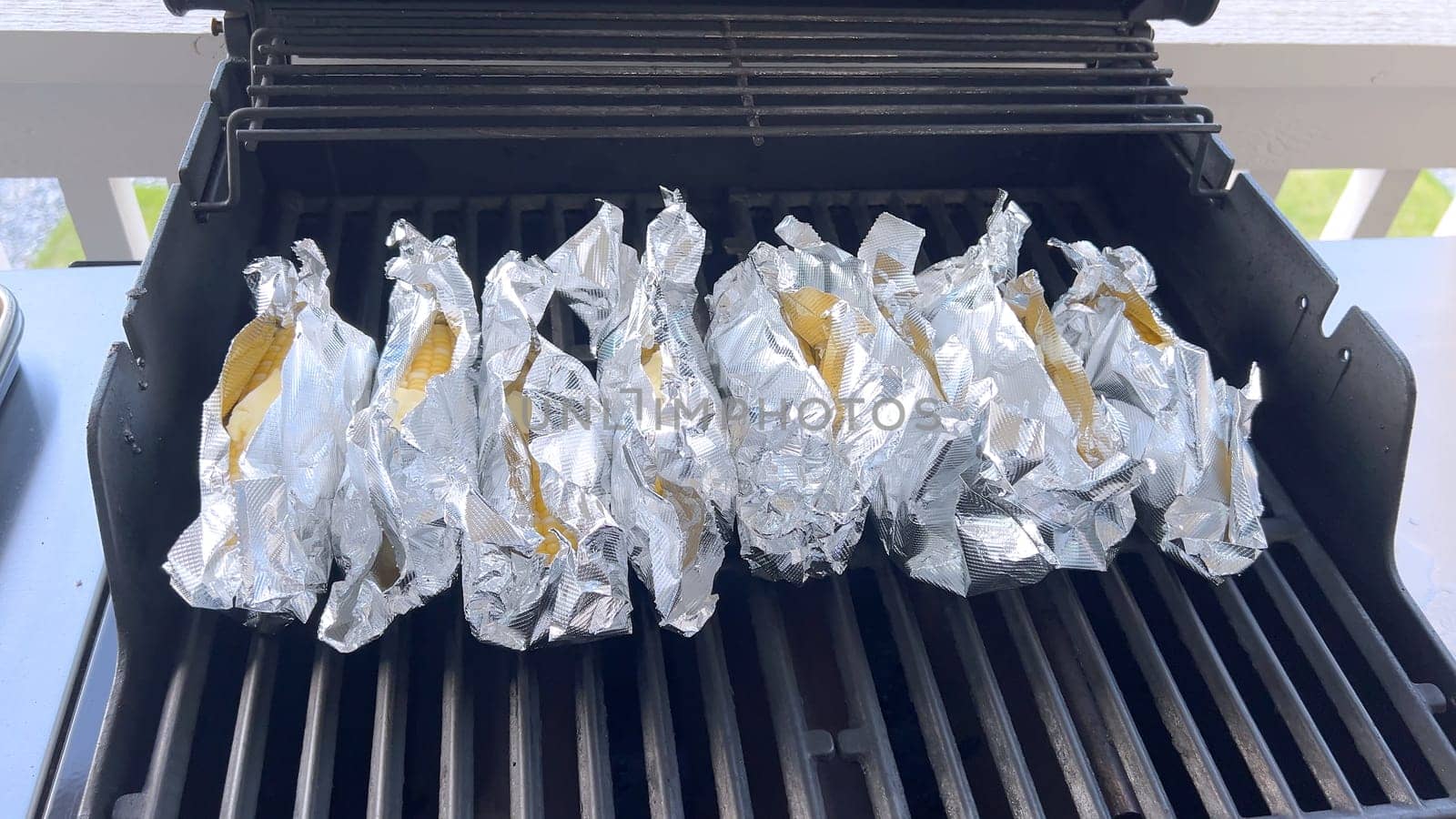 Corn on the Cob Wrapped in Foil Grilling on a Barbecue by arinahabich