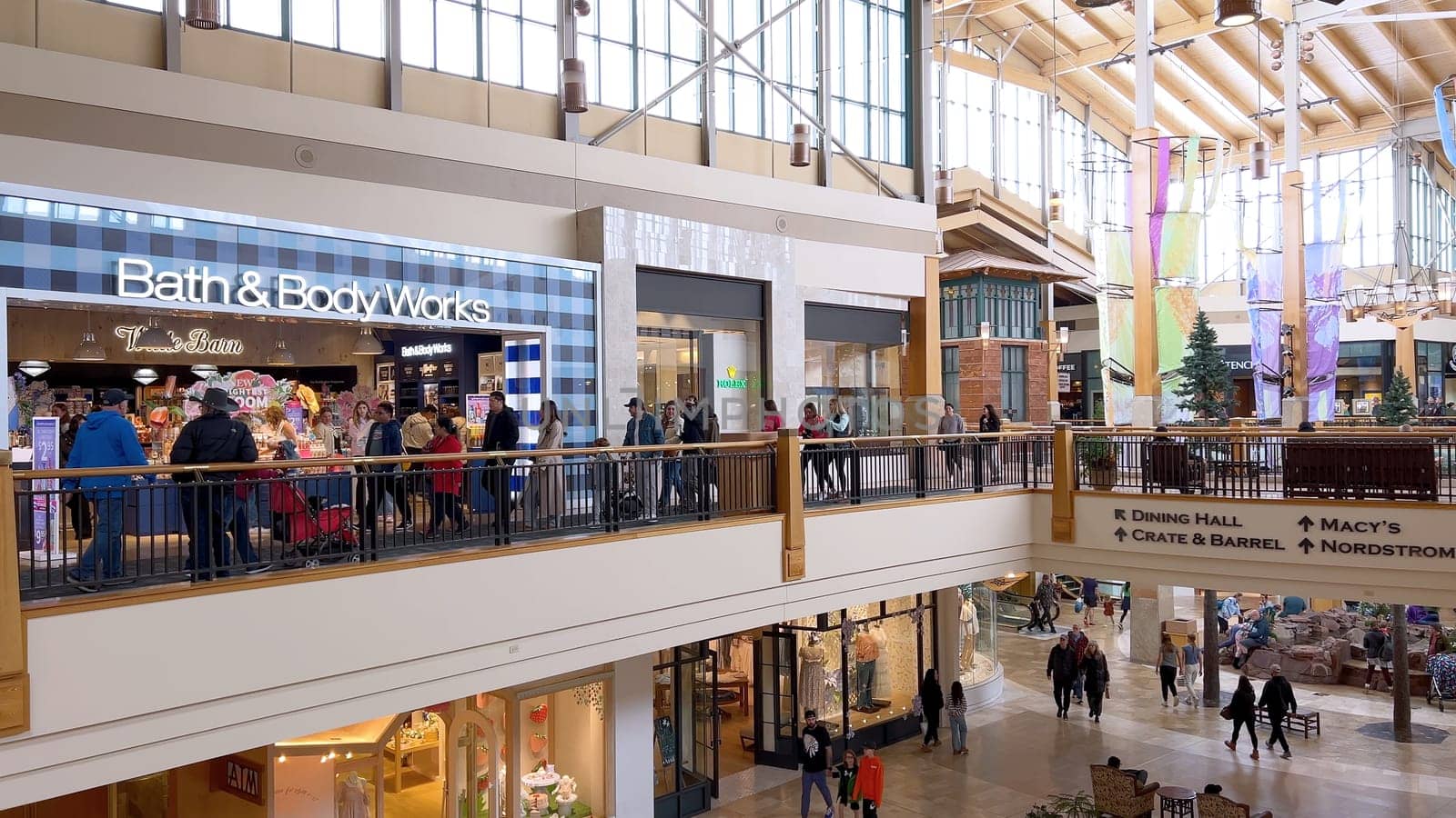 Denver, Colorado, USA-April 28, 2024- Capturing the expansive and airy interior of Park Meadows Mall, this image highlights the modern architectural style with wooden beams, large hanging lights, and a series of vibrant hanging ribbons, creating a lively shopping atmosphere.