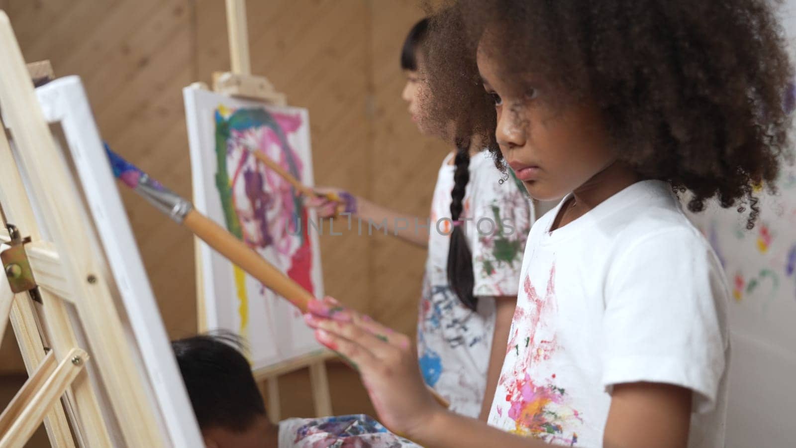 Happy creative african girl painted or draw canvas together with asian boy. Group of playful student create funny painting or artwork painted by watercolor. Creativity activity concept. Erudition.