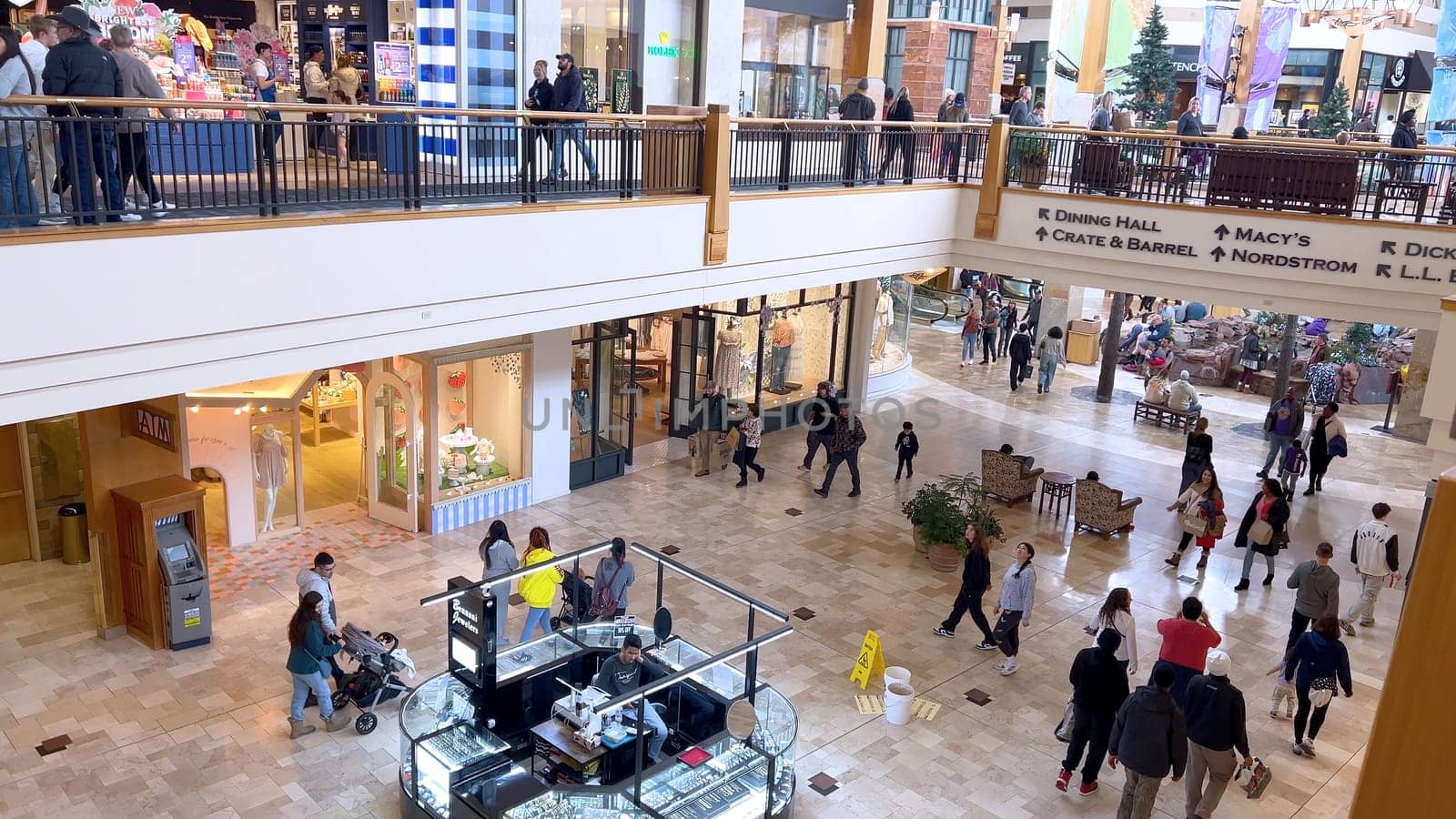 Denver, Colorado, USA-April 28, 2024- Capturing the expansive and airy interior of Park Meadows Mall, this image highlights the modern architectural style with wooden beams, large hanging lights, and a series of vibrant hanging ribbons, creating a lively shopping atmosphere.