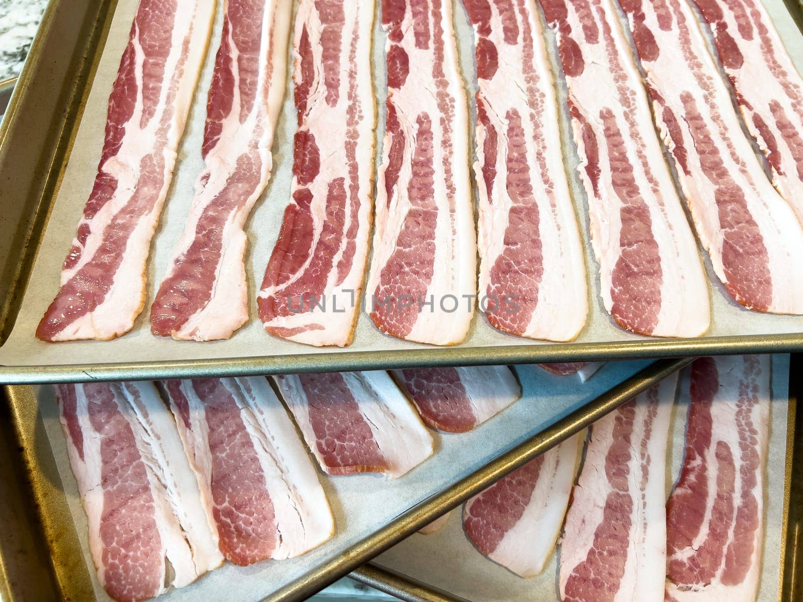 Raw Bacon Strips Ready for Cooking on a Baking Tray by arinahabich