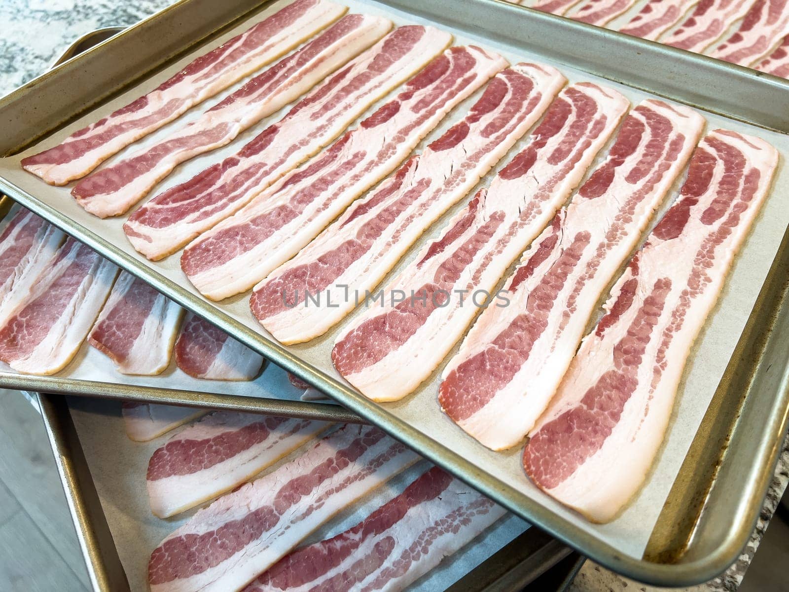 Neatly arranged raw bacon strips on a baking tray, prepared for cooking, capturing the fresh, uncooked look of this popular breakfast ingredient before it turns crispy and golden.