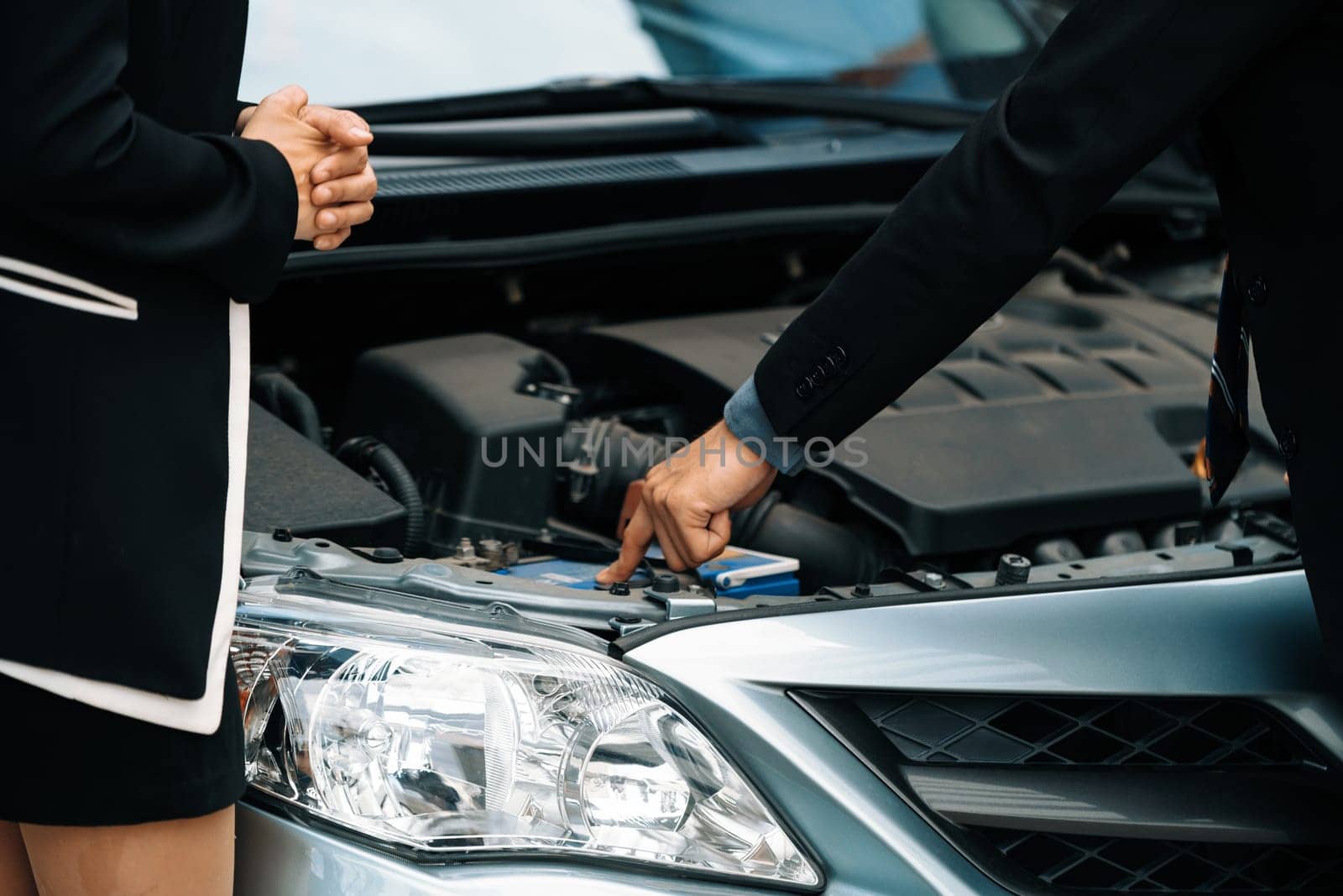 Man help woman fix the car problem. He pop up the car hood to repair the damaged part. uds