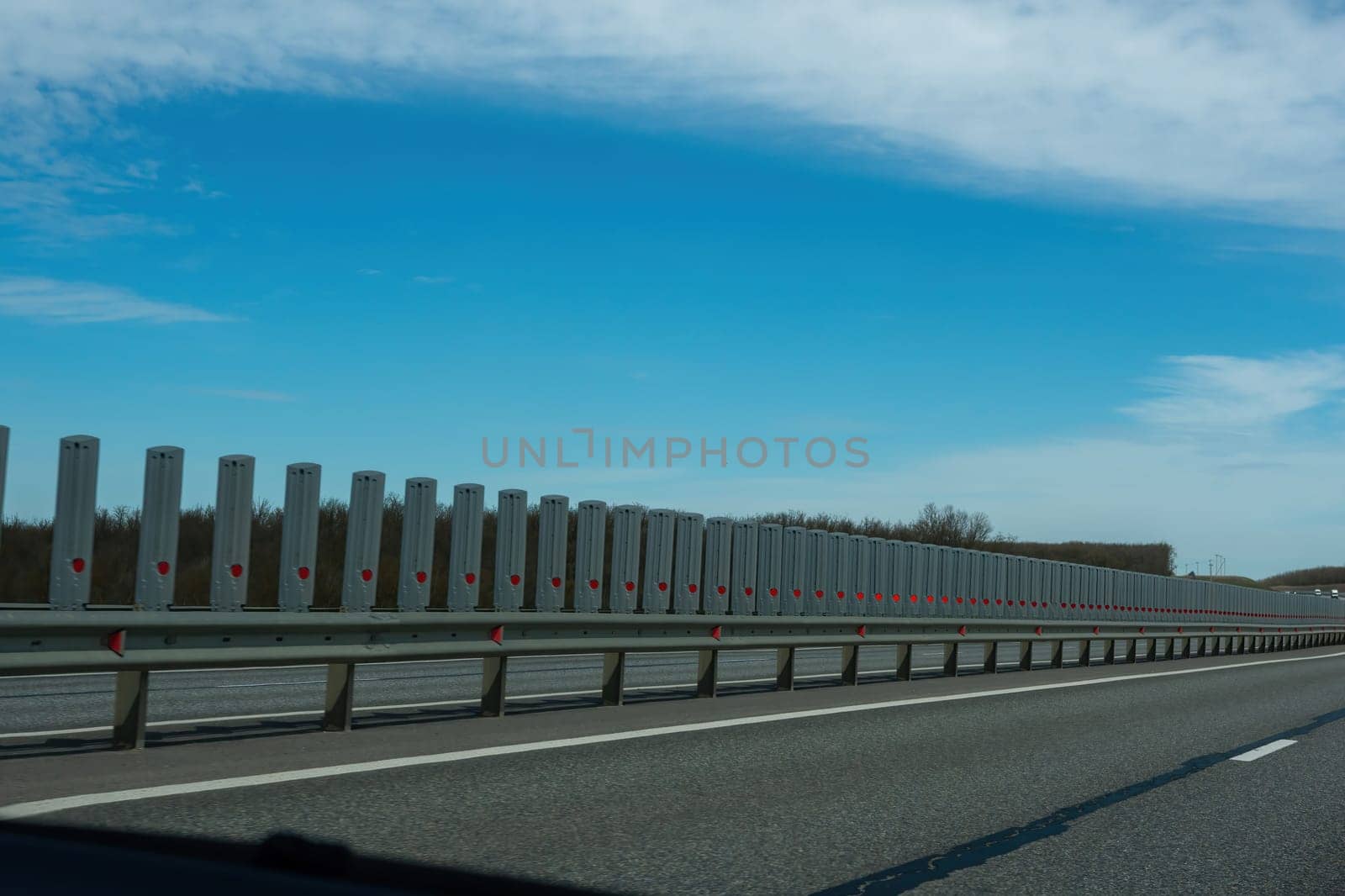 A road with a long line of metal posts with red hearts on them. The road is empty and the sky is clear. by Matiunina