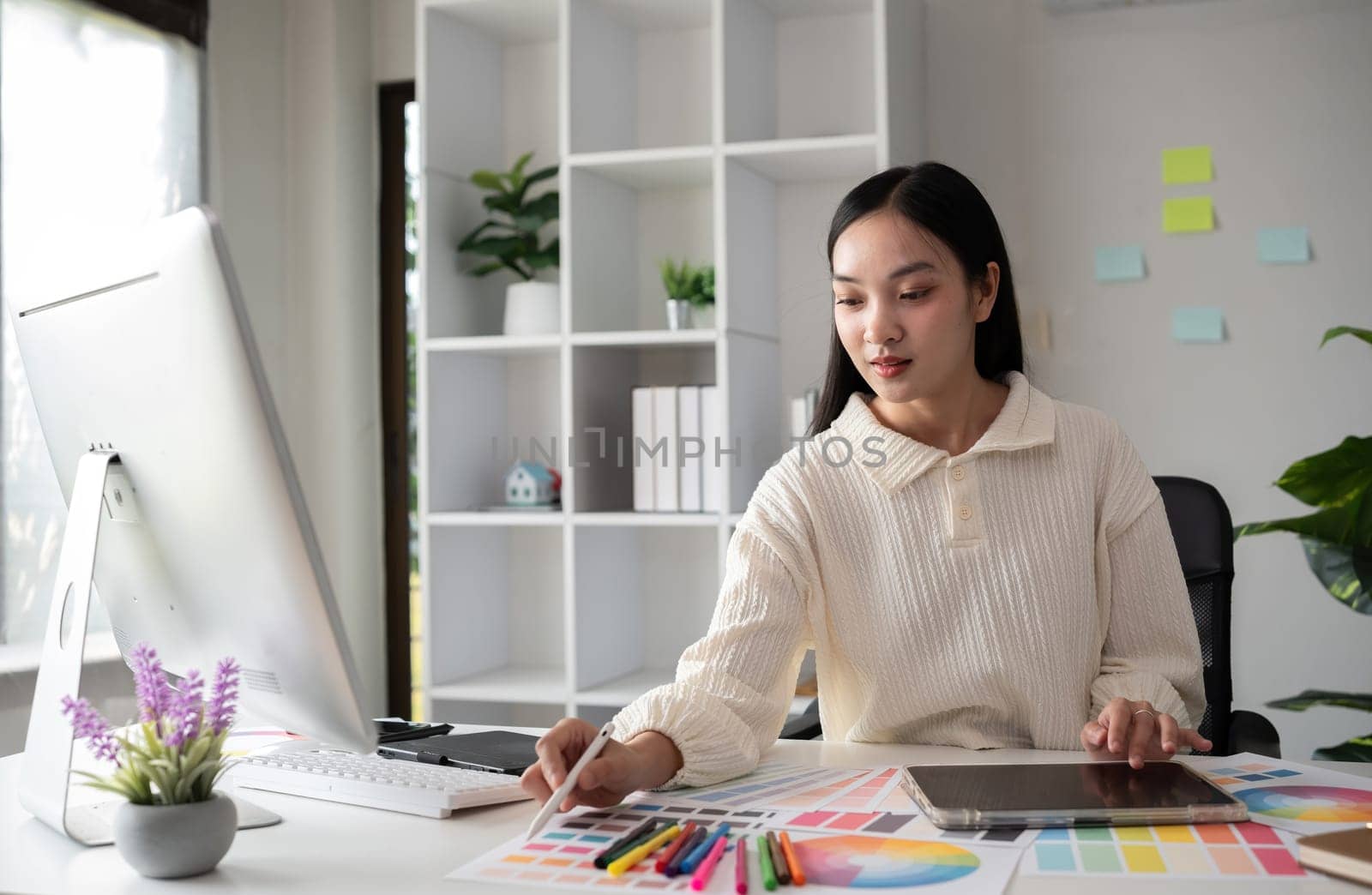 Female designer working in graphic design on computer Sit and choose colors and work intently in your office..