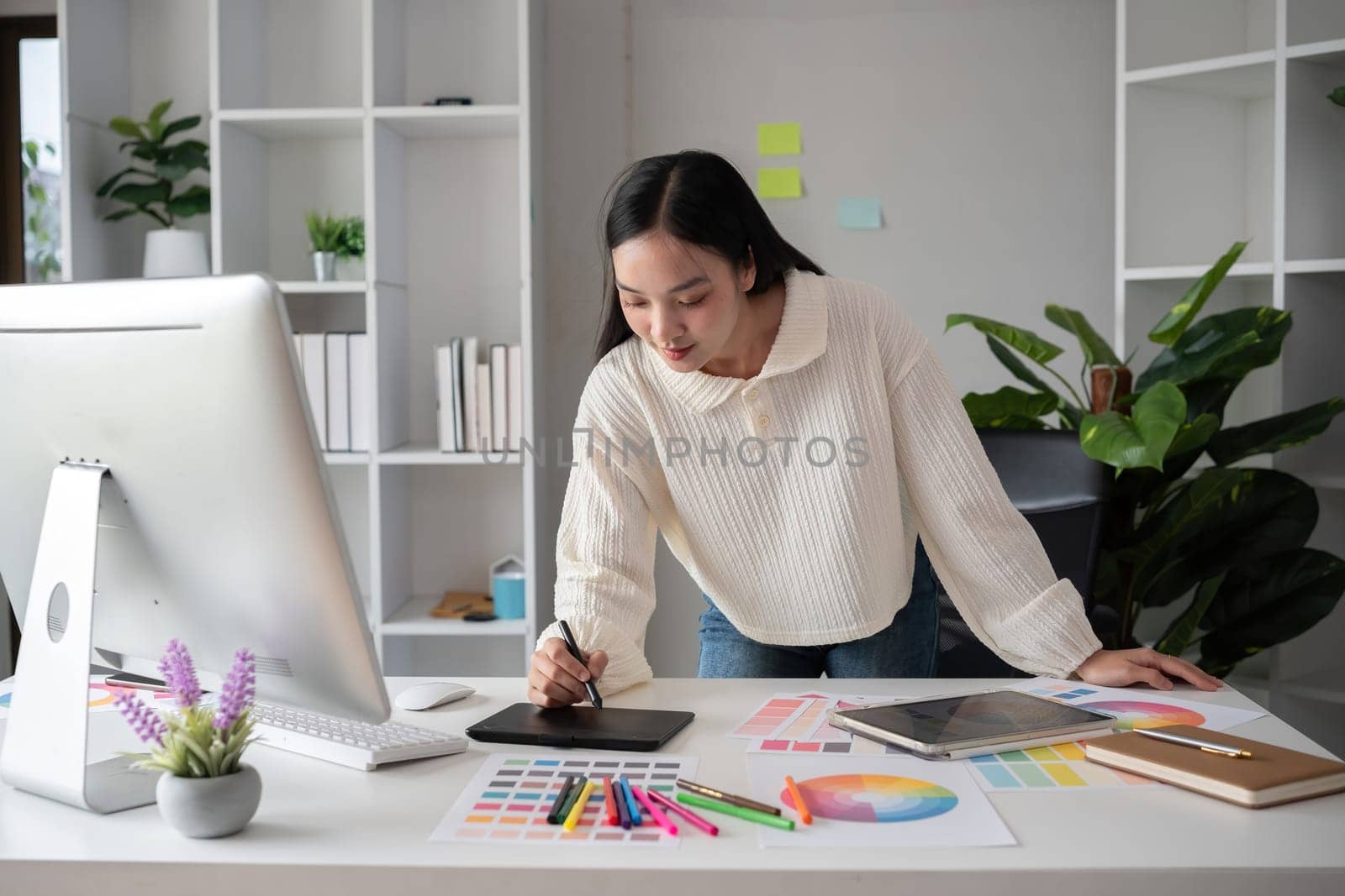 Female designer working in graphic design on computer Sit and choose colors and work intently in your office. by wichayada