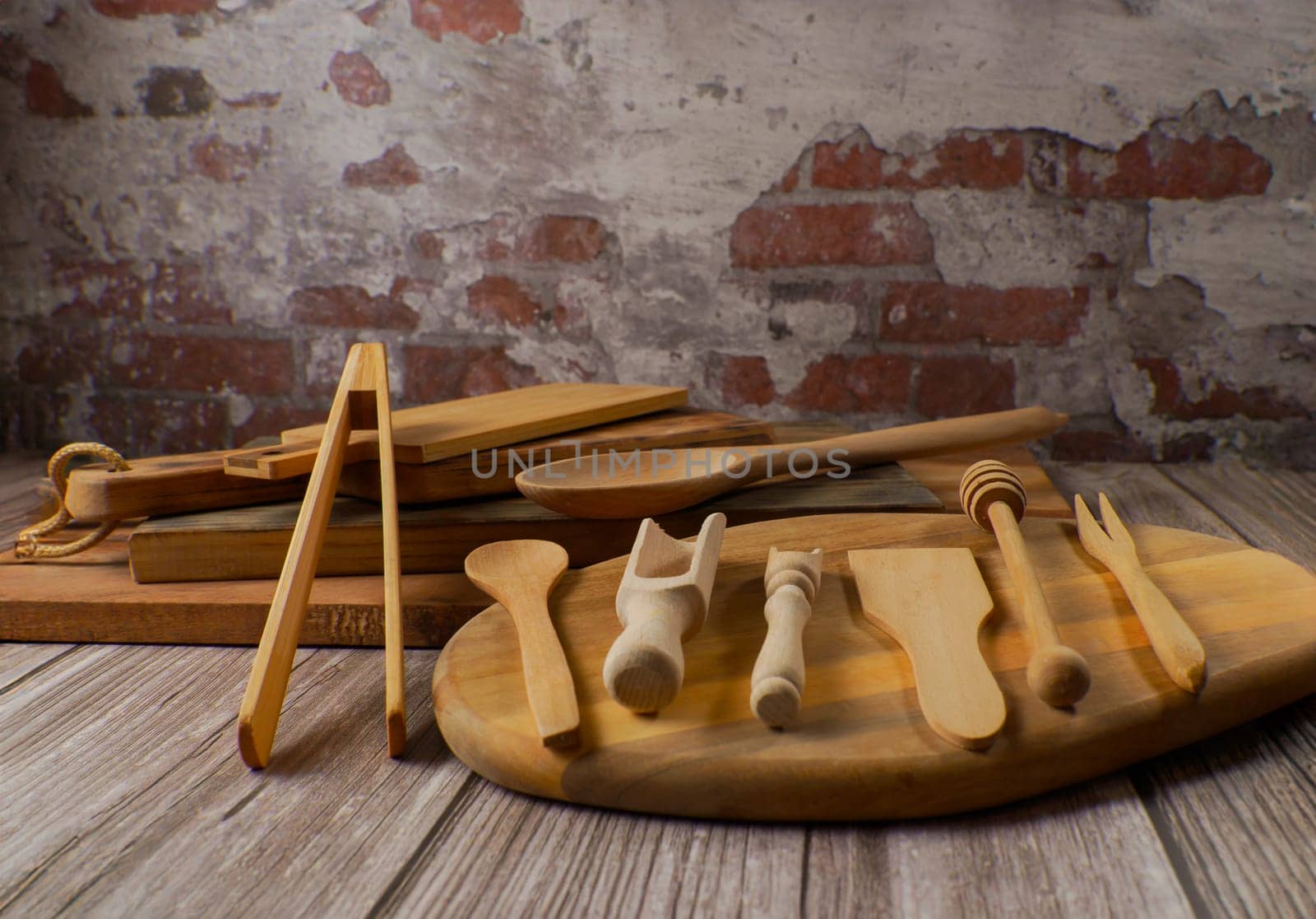 various types of wooden kitchen utensils on wooden cutting boards with a brick wall backing