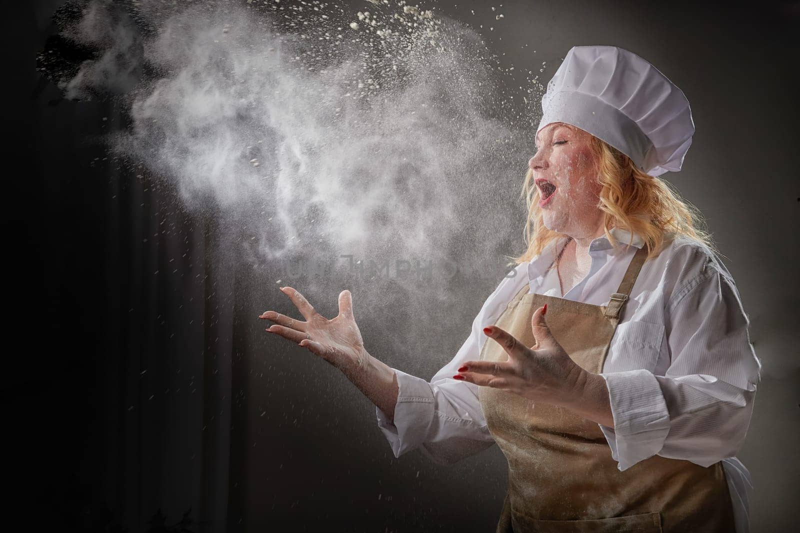 Fat funny female cook in a hat and apron posing and taking selfie in the kitchen with flour. Cooking, body positive, cloud, smoke, flour