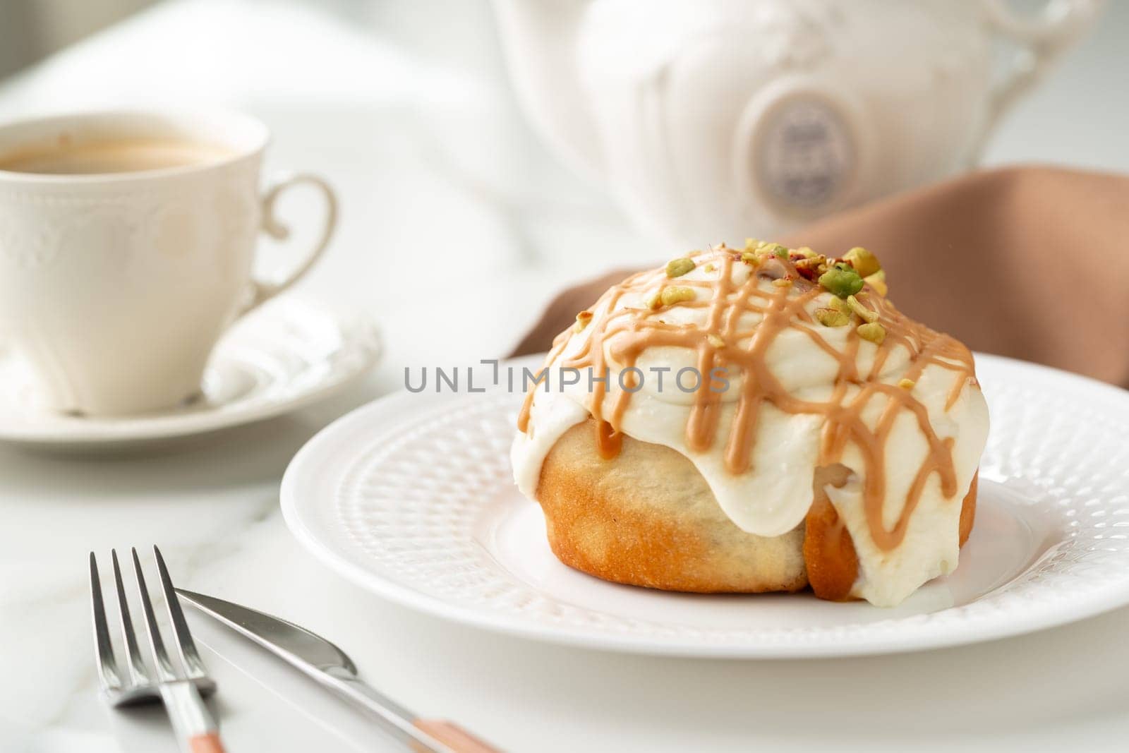 Cinnamon roll bun with icing on plate close up