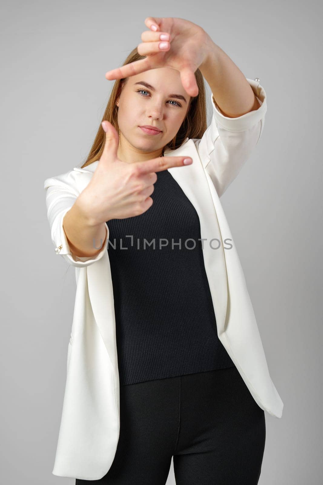 Young Woman Making Frame Gesture With Hands Against a Neutral Background in studio