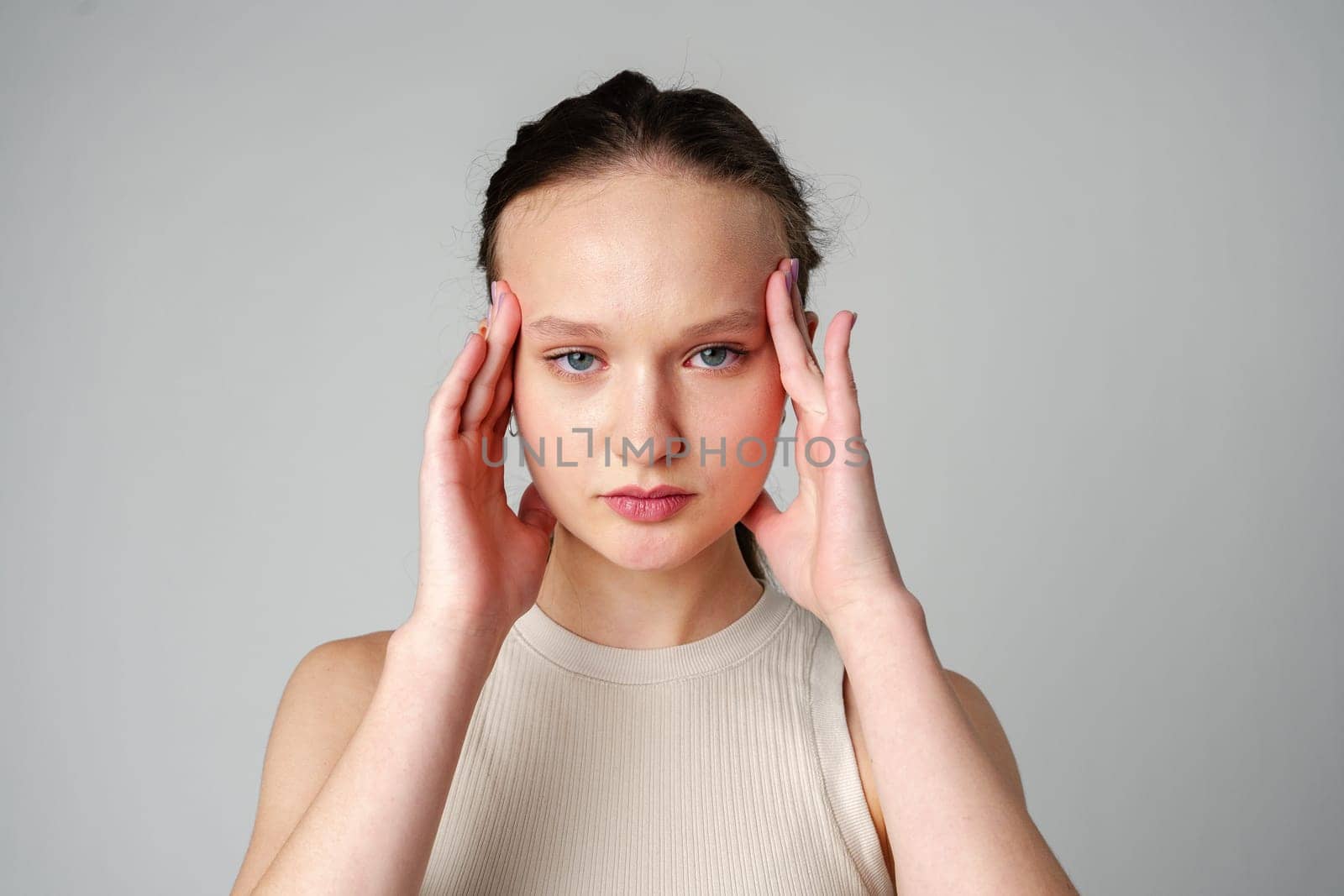Young Woman Grimacing in Displeasure Against a Neutral Background by Fabrikasimf