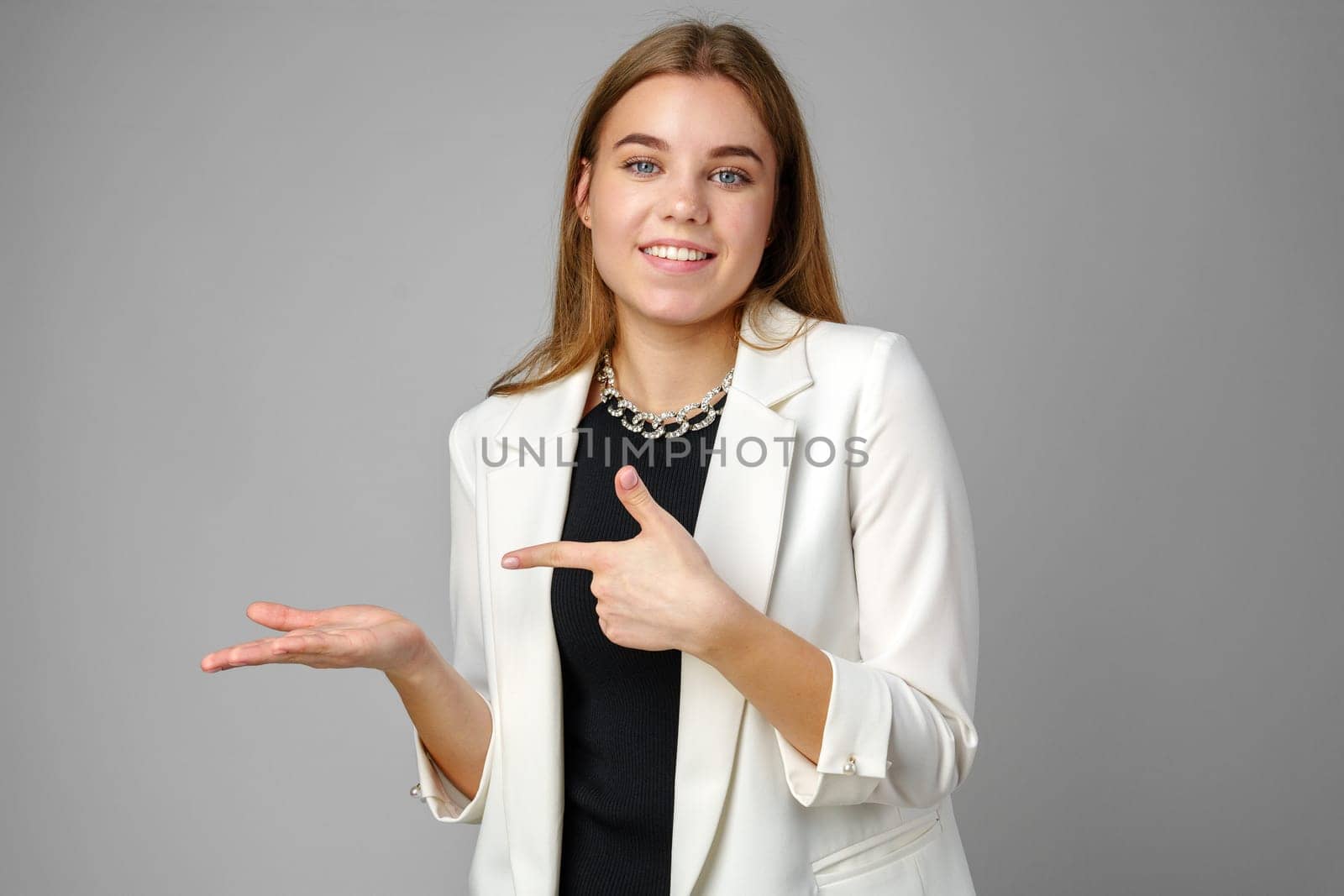 Confident Young Businesswoman Presenting With Hand Gesture in Studio Setting by Fabrikasimf