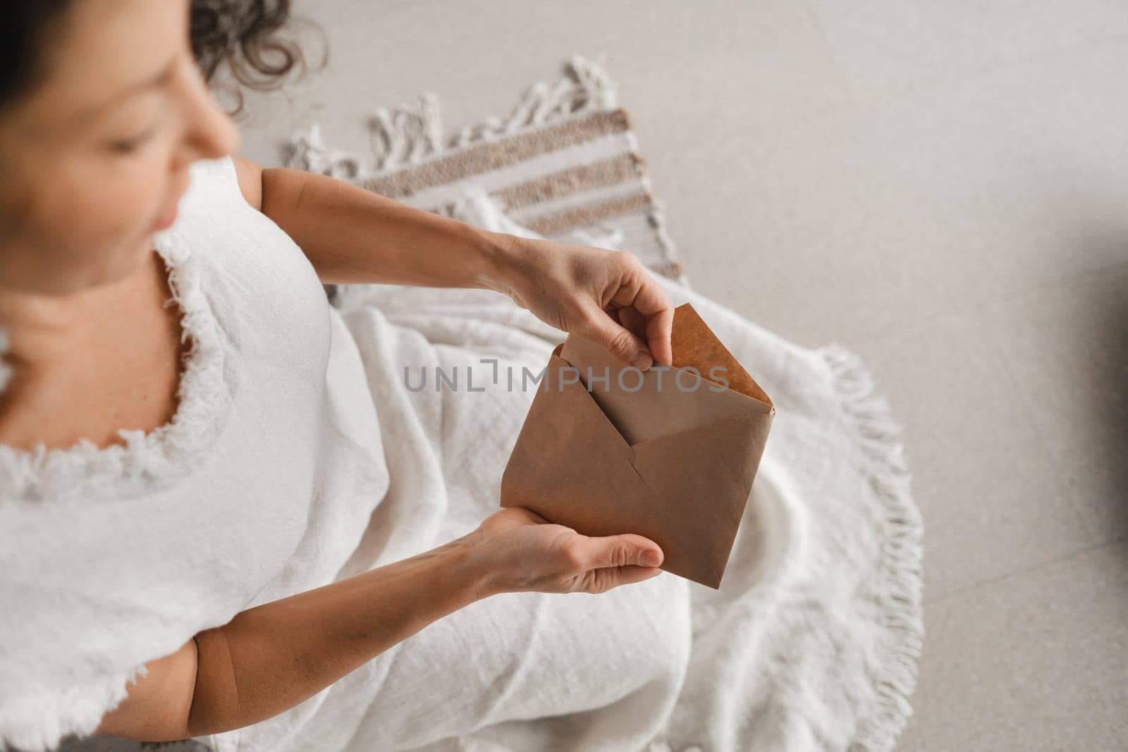 A woman in white clothes holds an envelope with a wish in her hands. The concept of a women's circle.