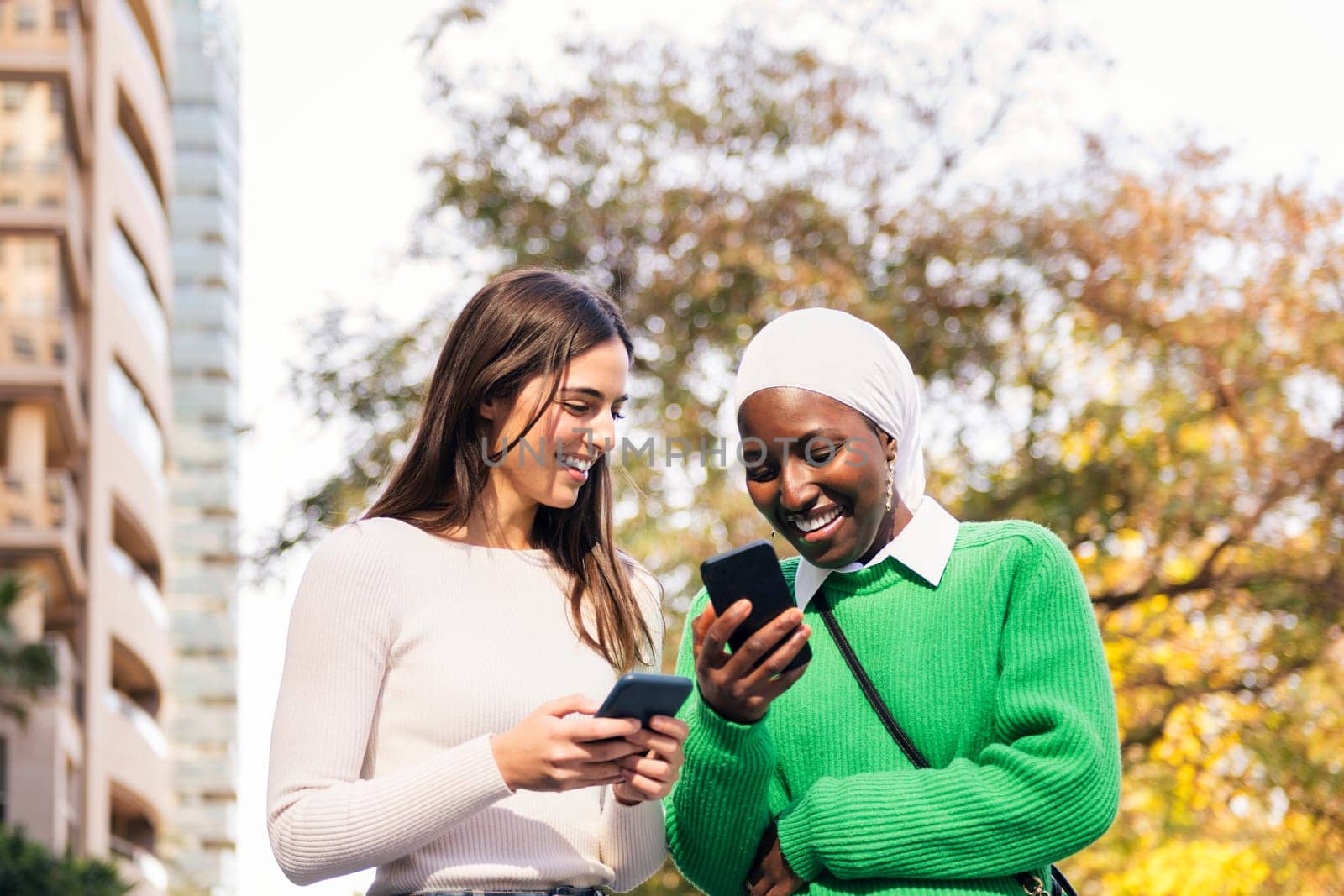 two women smiling happy looking their cell phones by raulmelldo