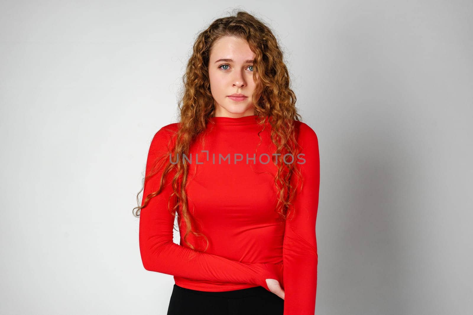 Woman With Curly Hair Standing on Gray Background by Fabrikasimf