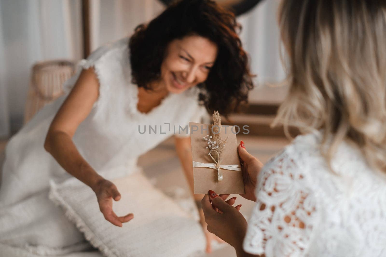 A woman in white clothes passes an envelope with a wish to another woman. The concept of the women's circle.